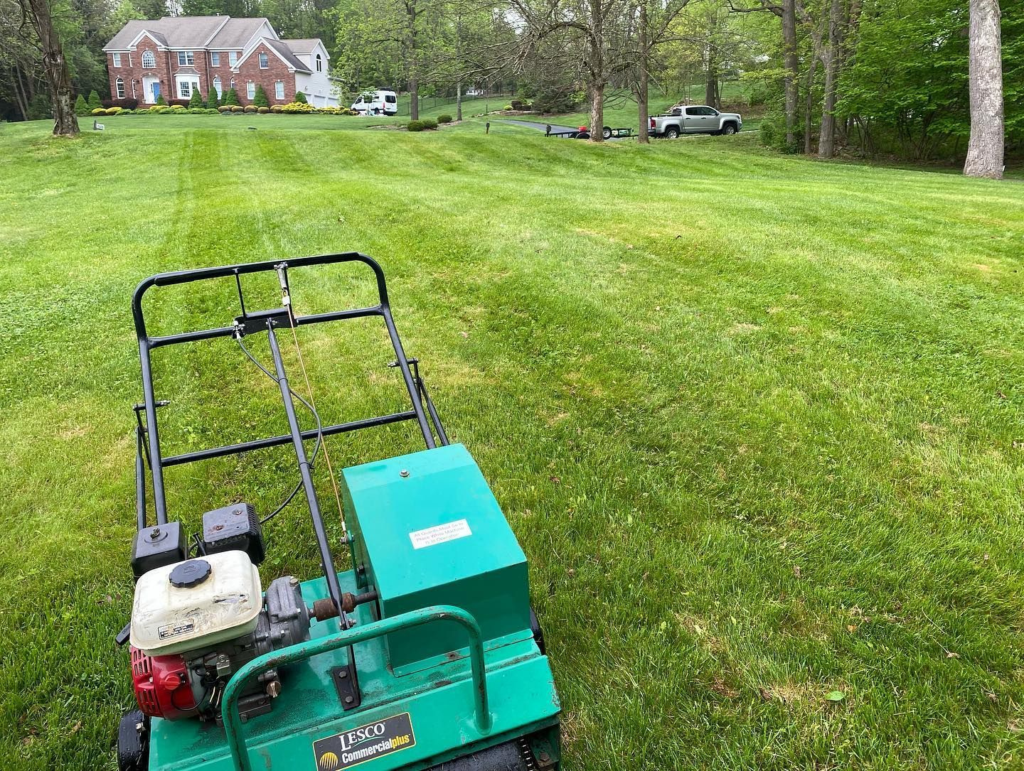 A green lawn mower is sitting on top of a lush green lawn.