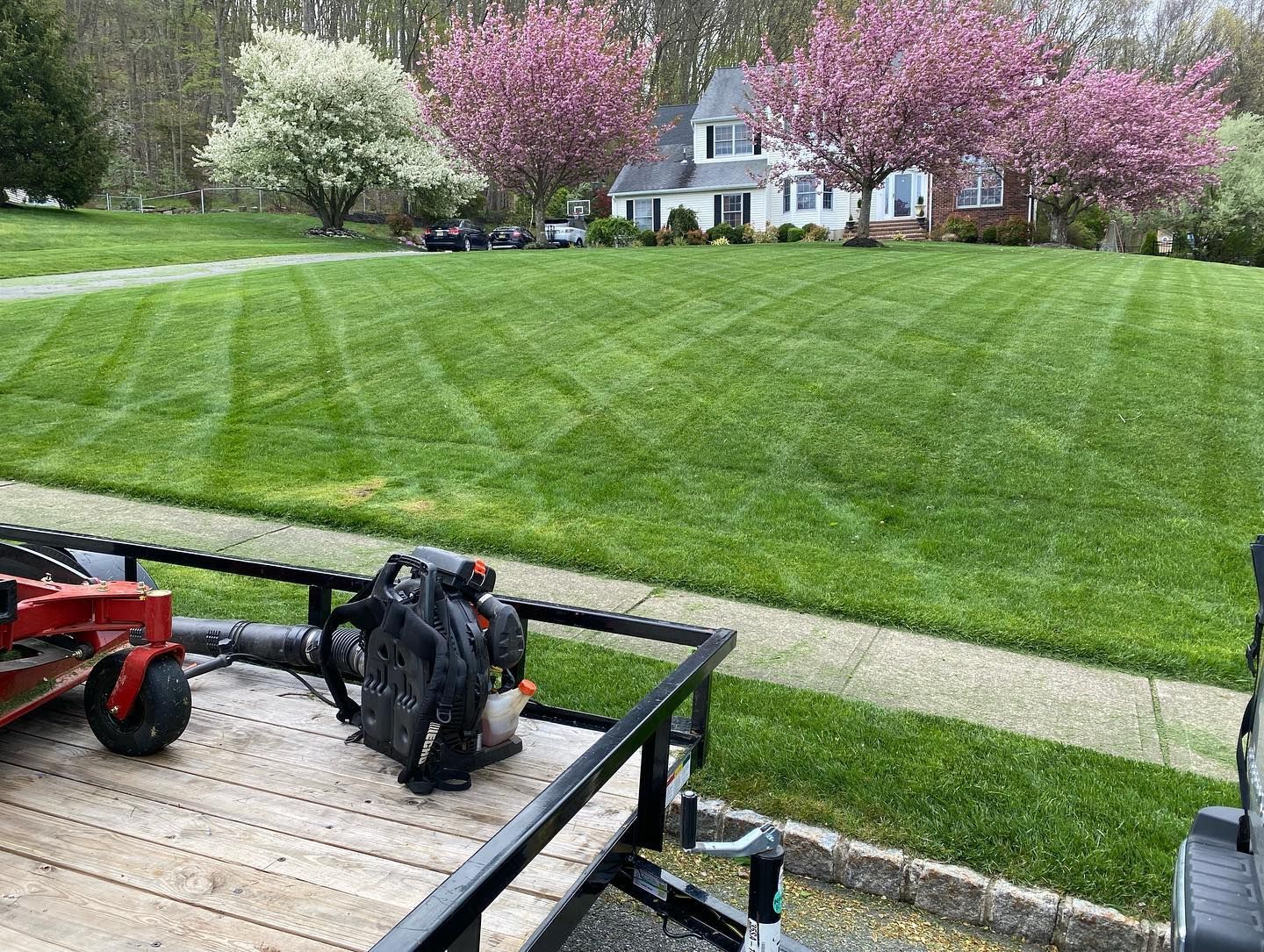 A lawn mower is sitting on top of a trailer next to a lush green lawn.