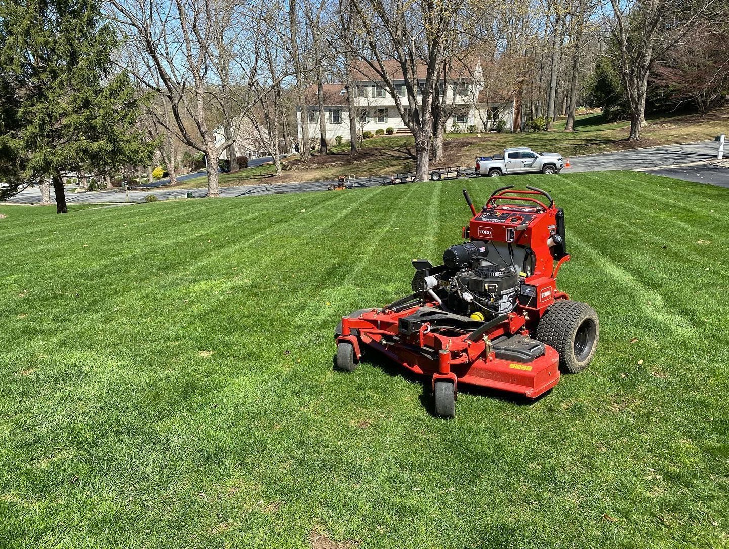 A red lawn mower is sitting on top of a lush green lawn.