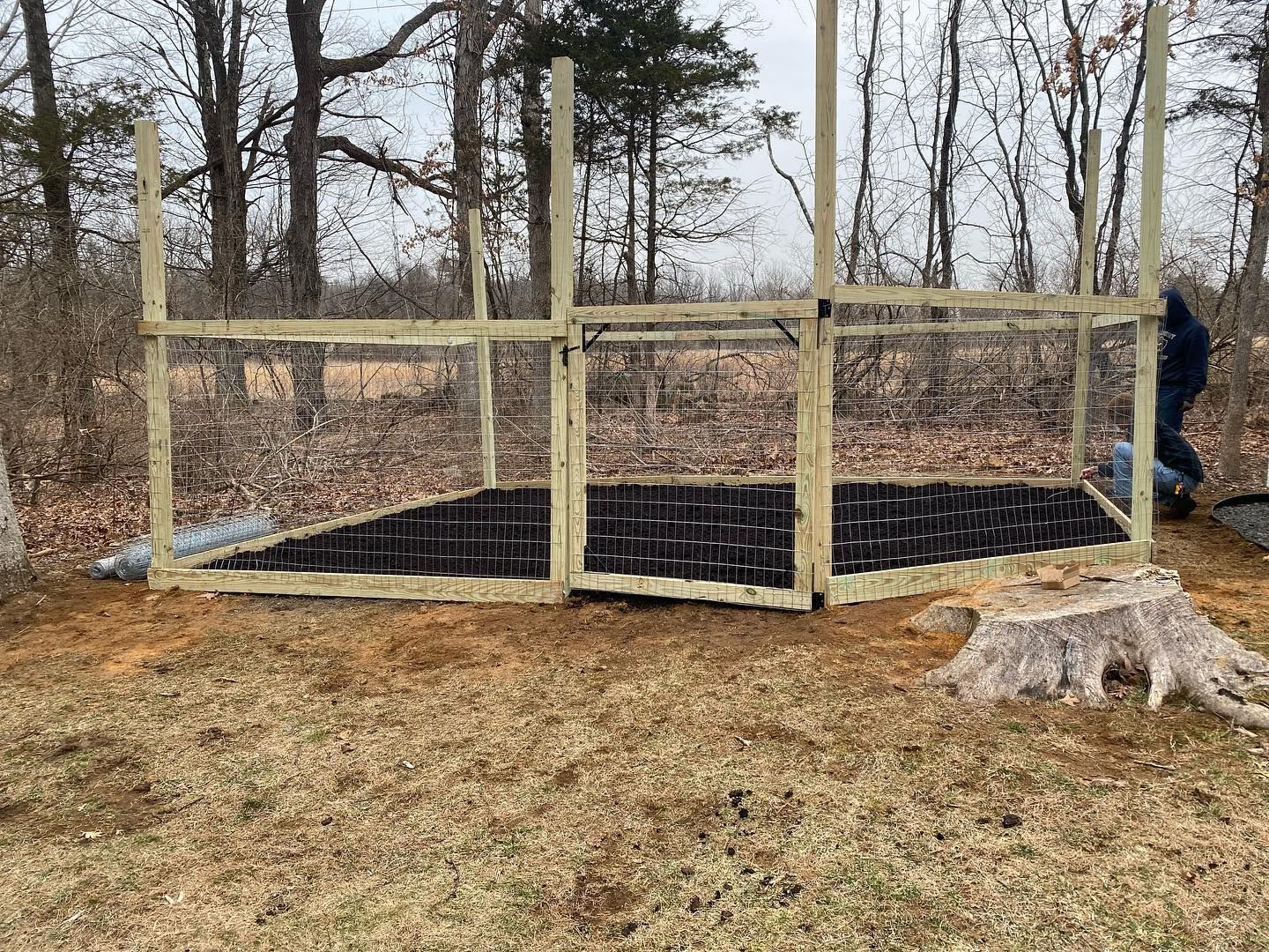 A man is standing next to a wooden fence in a yard.