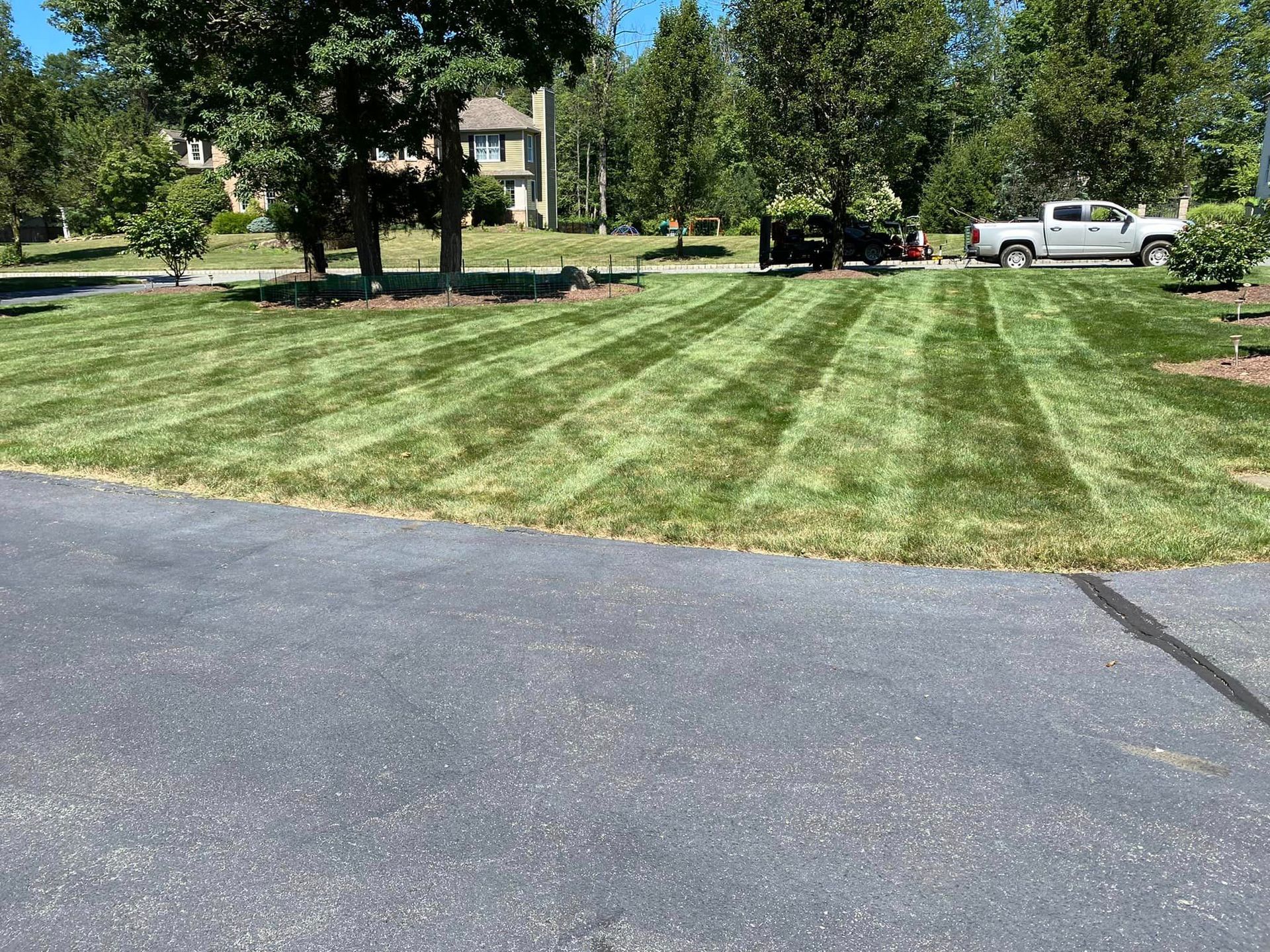 A truck is parked in a driveway next to a lush green lawn.