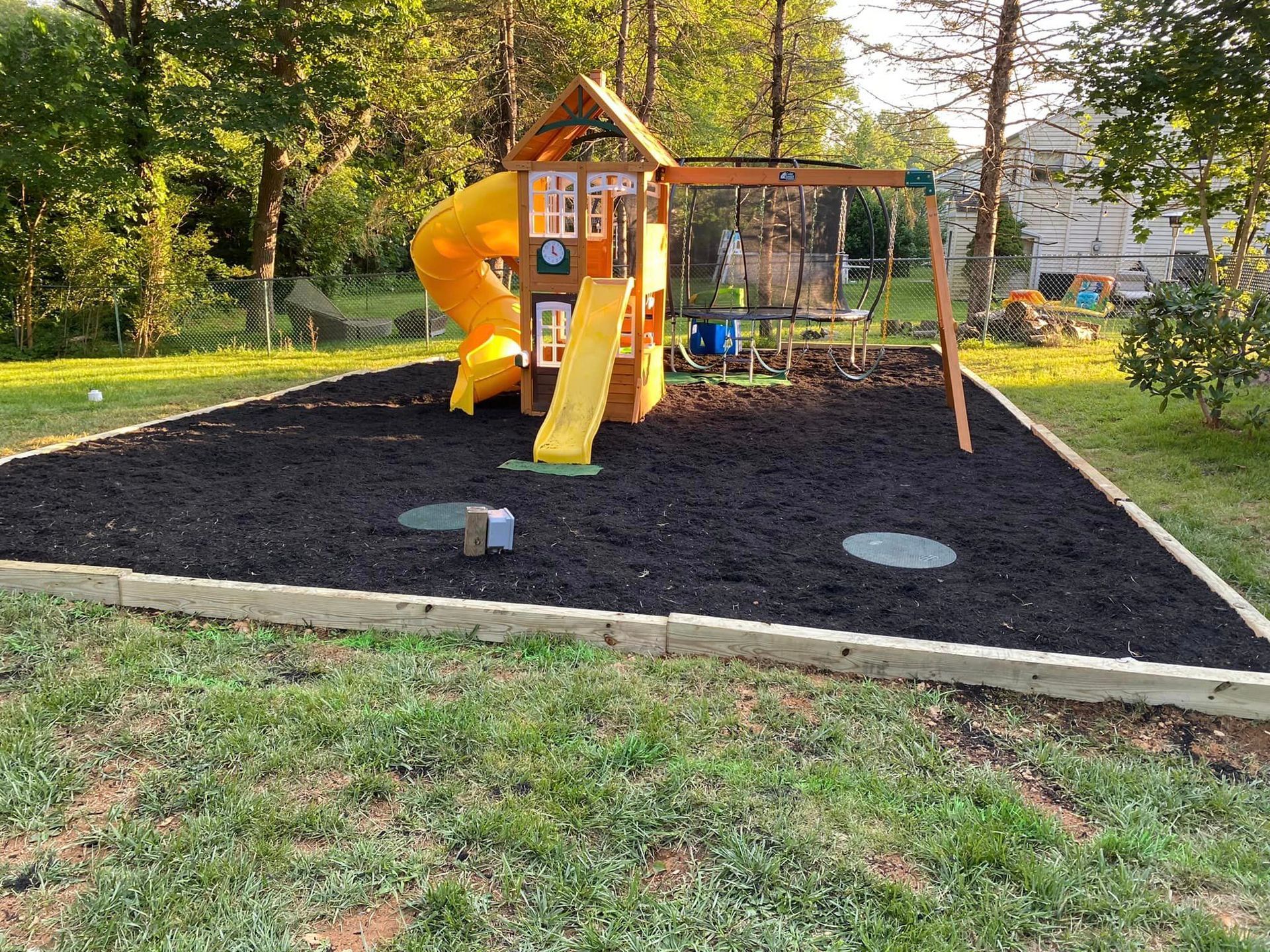 A playground with a slide and swings in a backyard.