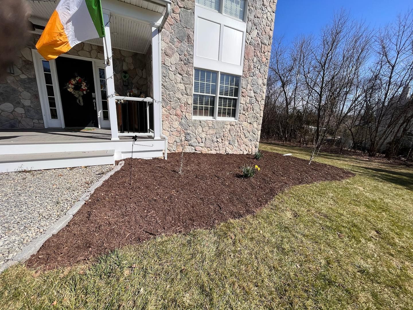A house with a flag on the porch and a lawn in front of it.