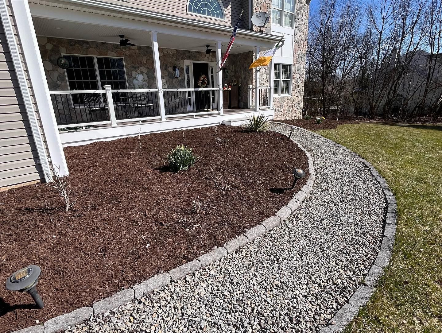 A gravel walkway leading to a house with a porch.