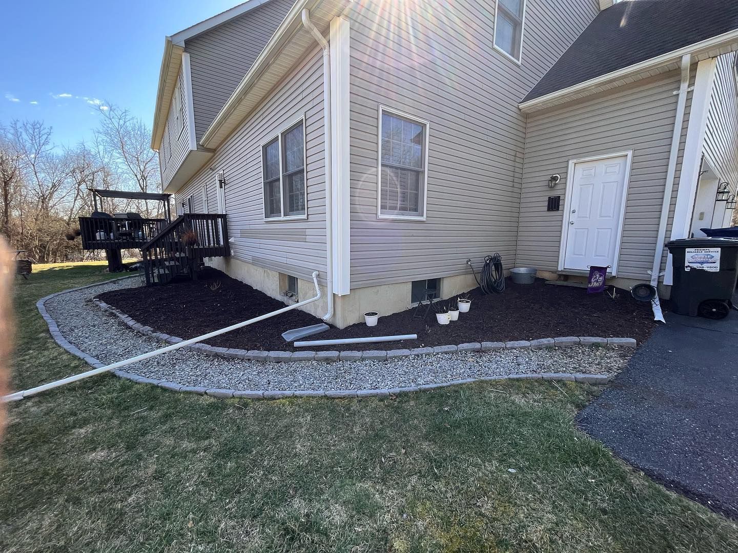 A house with a deck and a lawn in front of it.