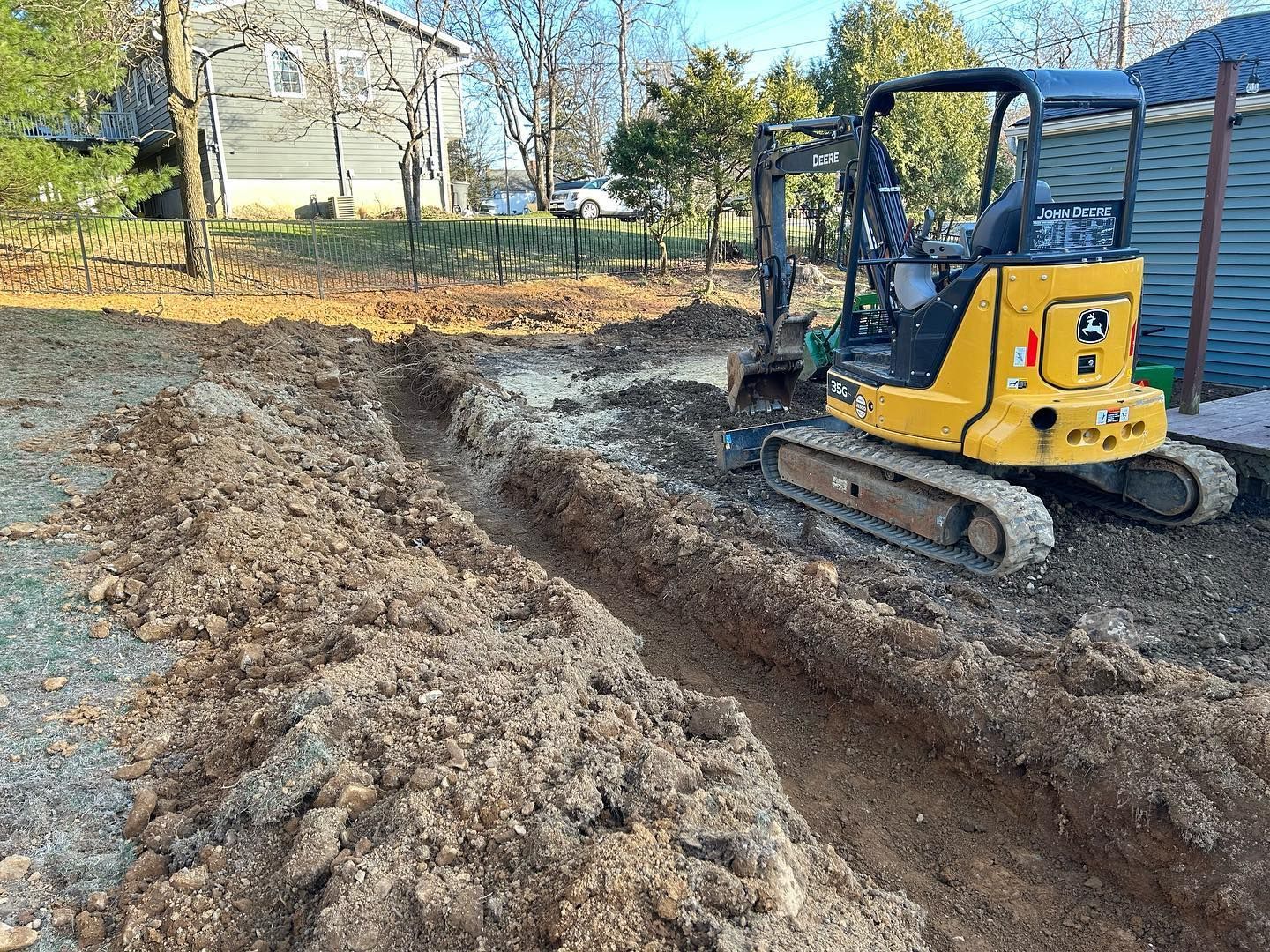 A small yellow excavator is digging a hole in the dirt.