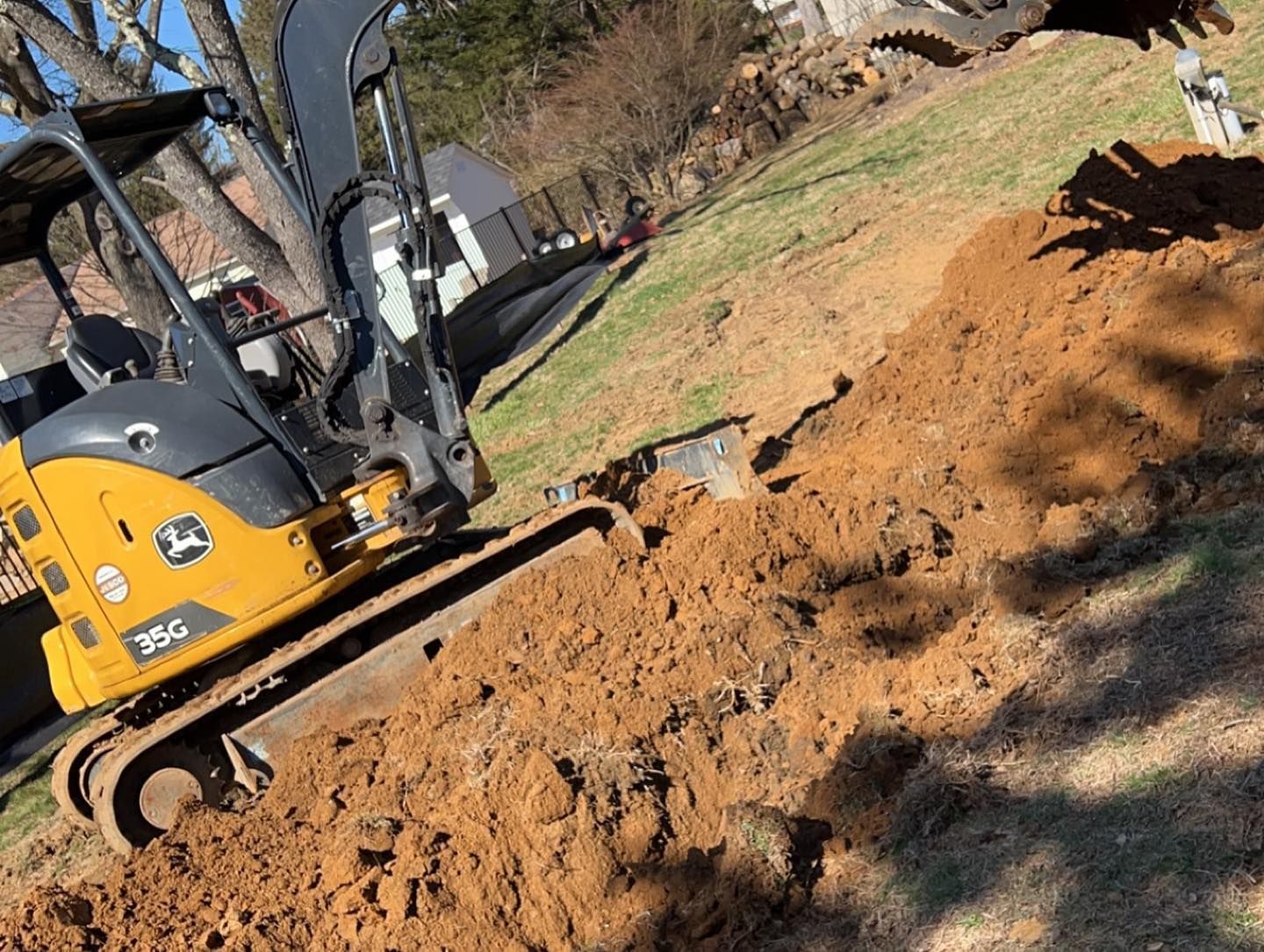 A yellow and black excavator is digging a hole in the dirt.