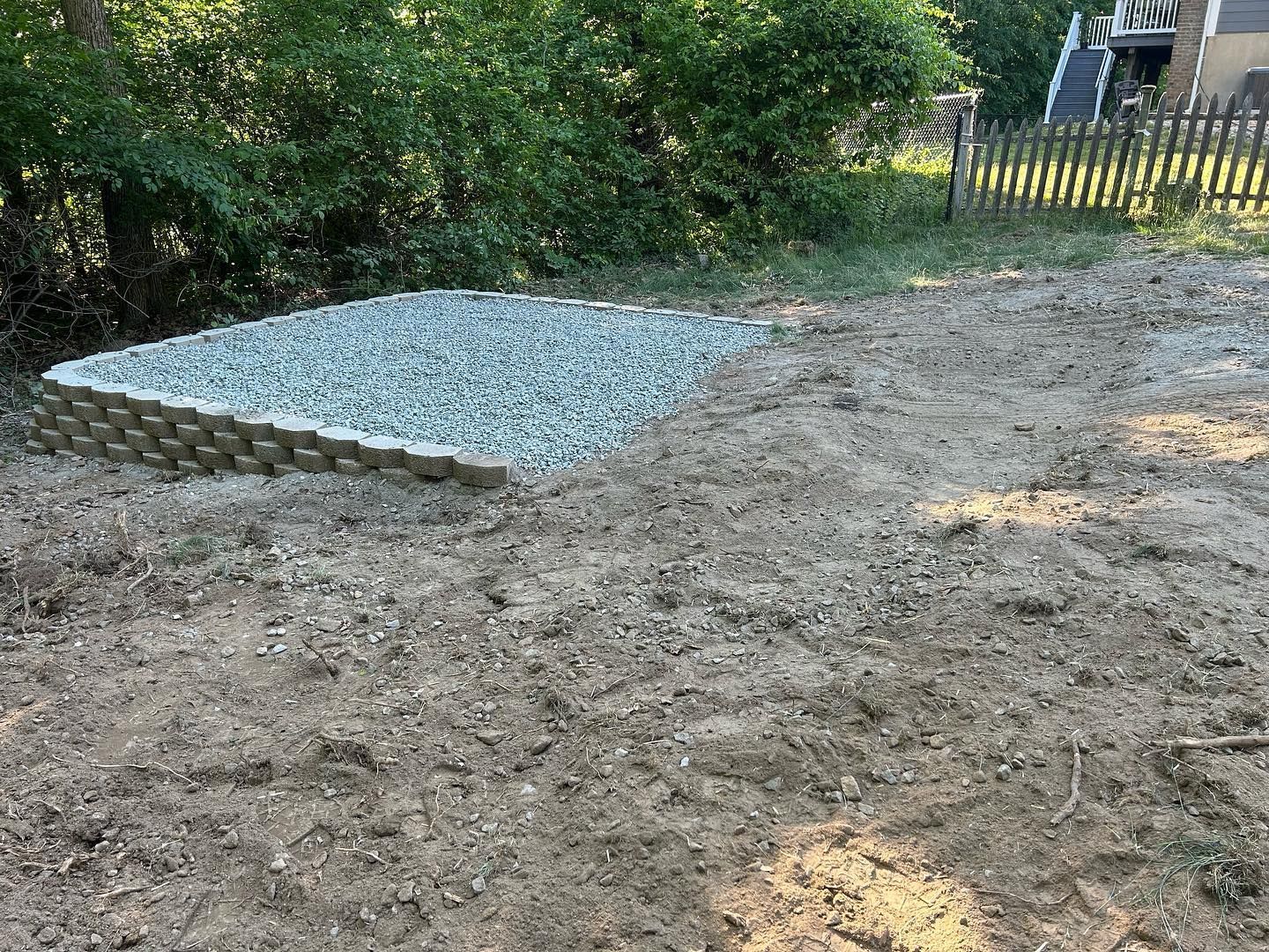 A pile of gravel is sitting in the middle of a dirt field.