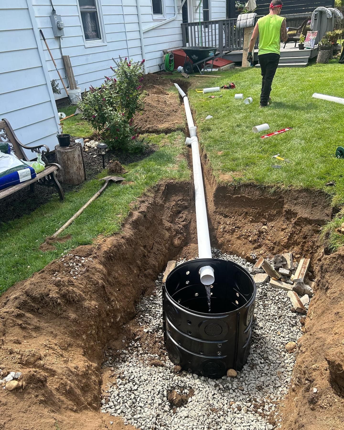 A man is standing in a hole in the ground in front of a house.