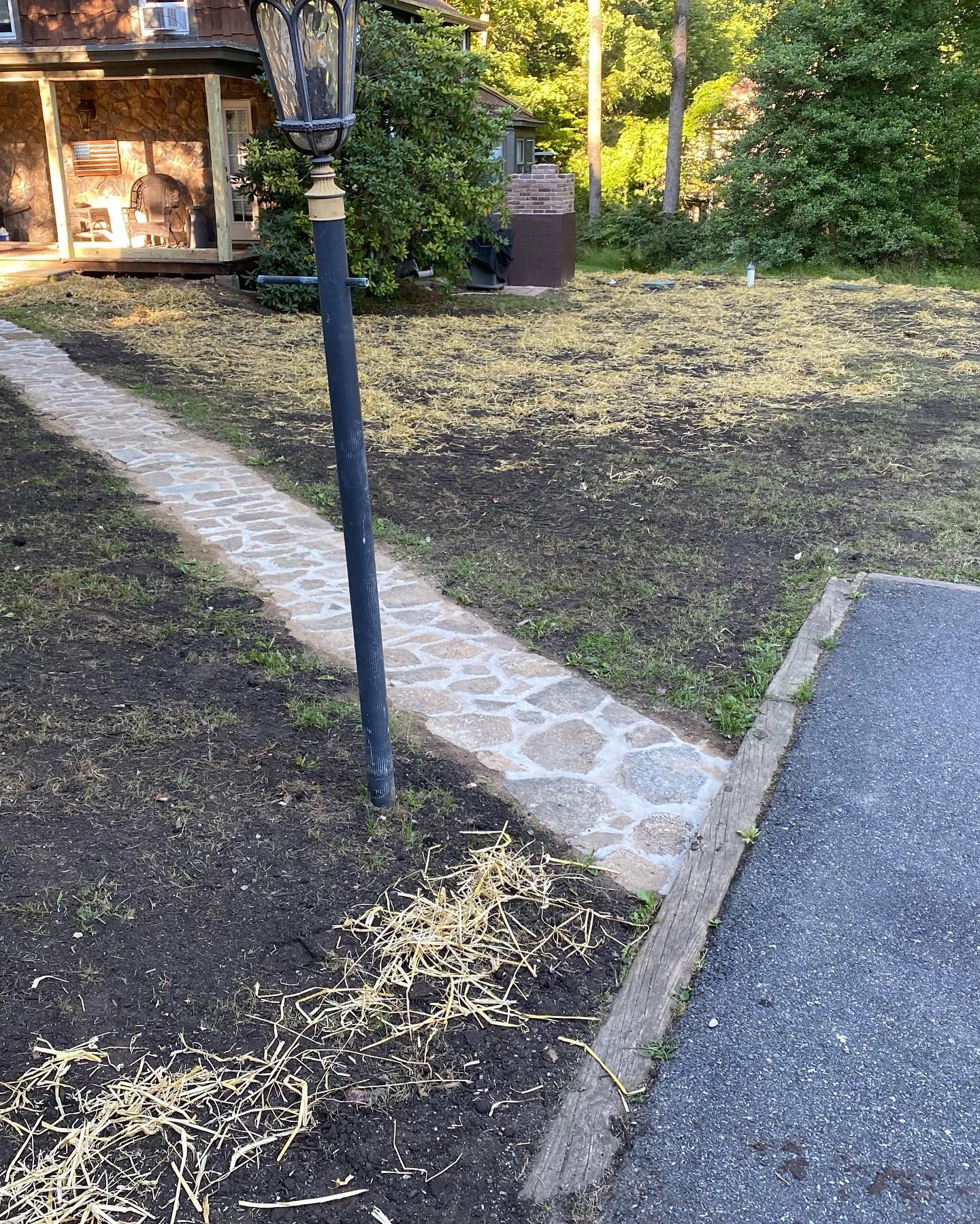 A stone walkway leading to a house with a lamp post.