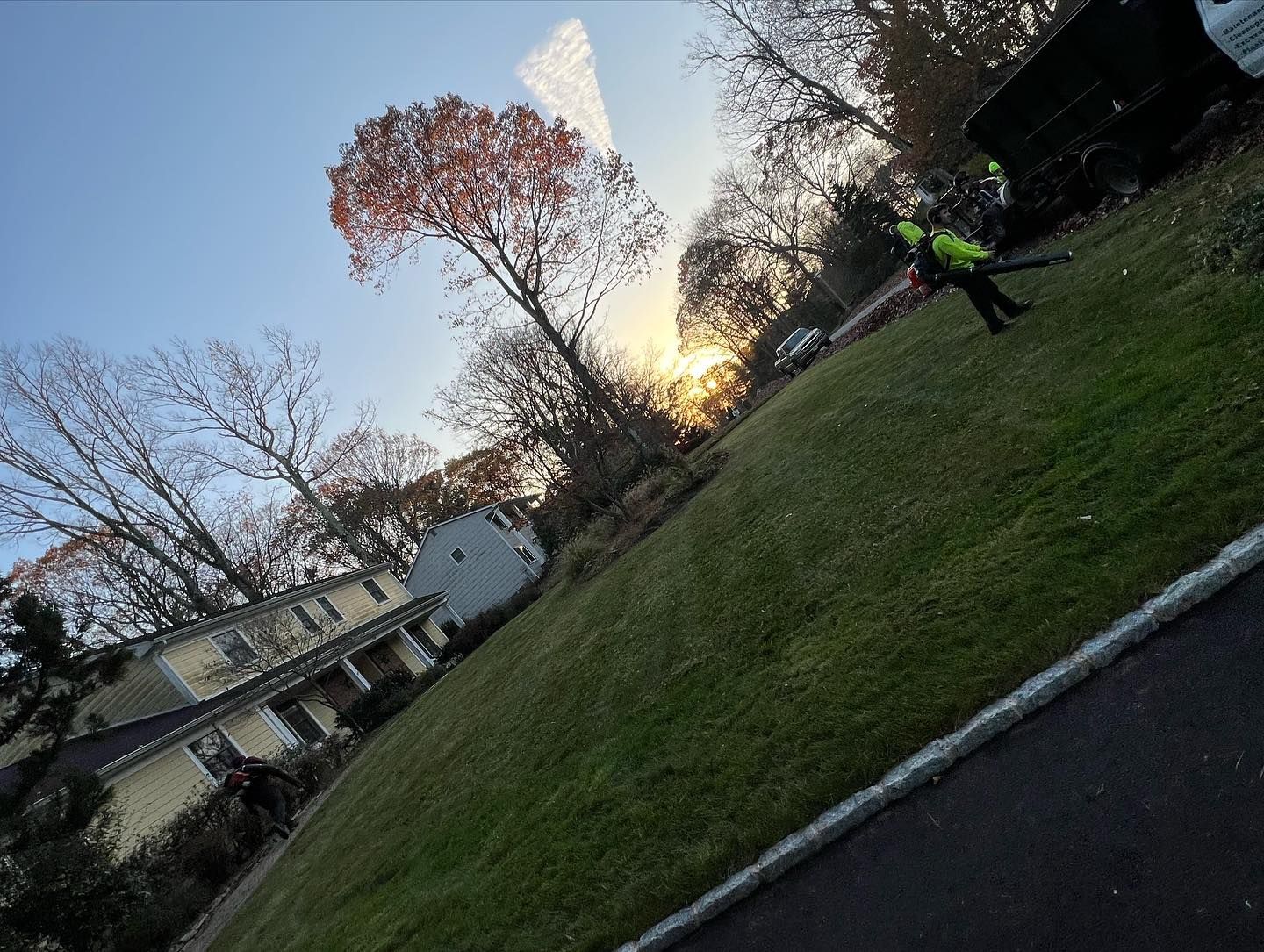 A group of people are standing on a lush green lawn in front of a house