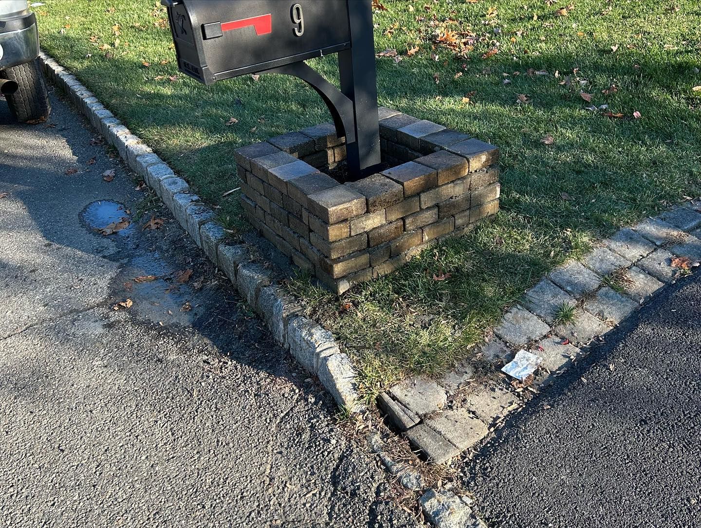 A black mailbox is sitting on top of a brick pillar.