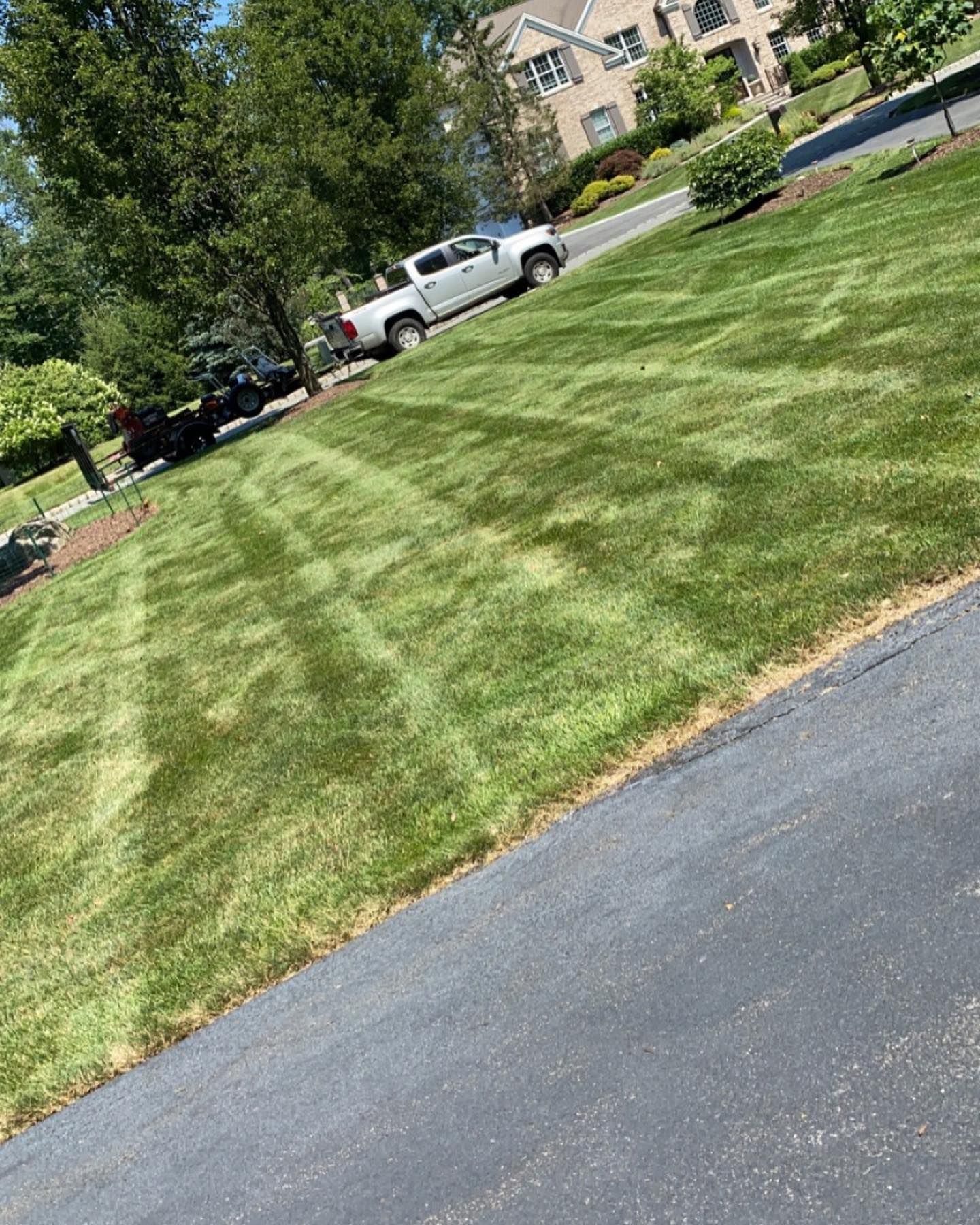 A truck is parked on the side of the road next to a lush green lawn.
