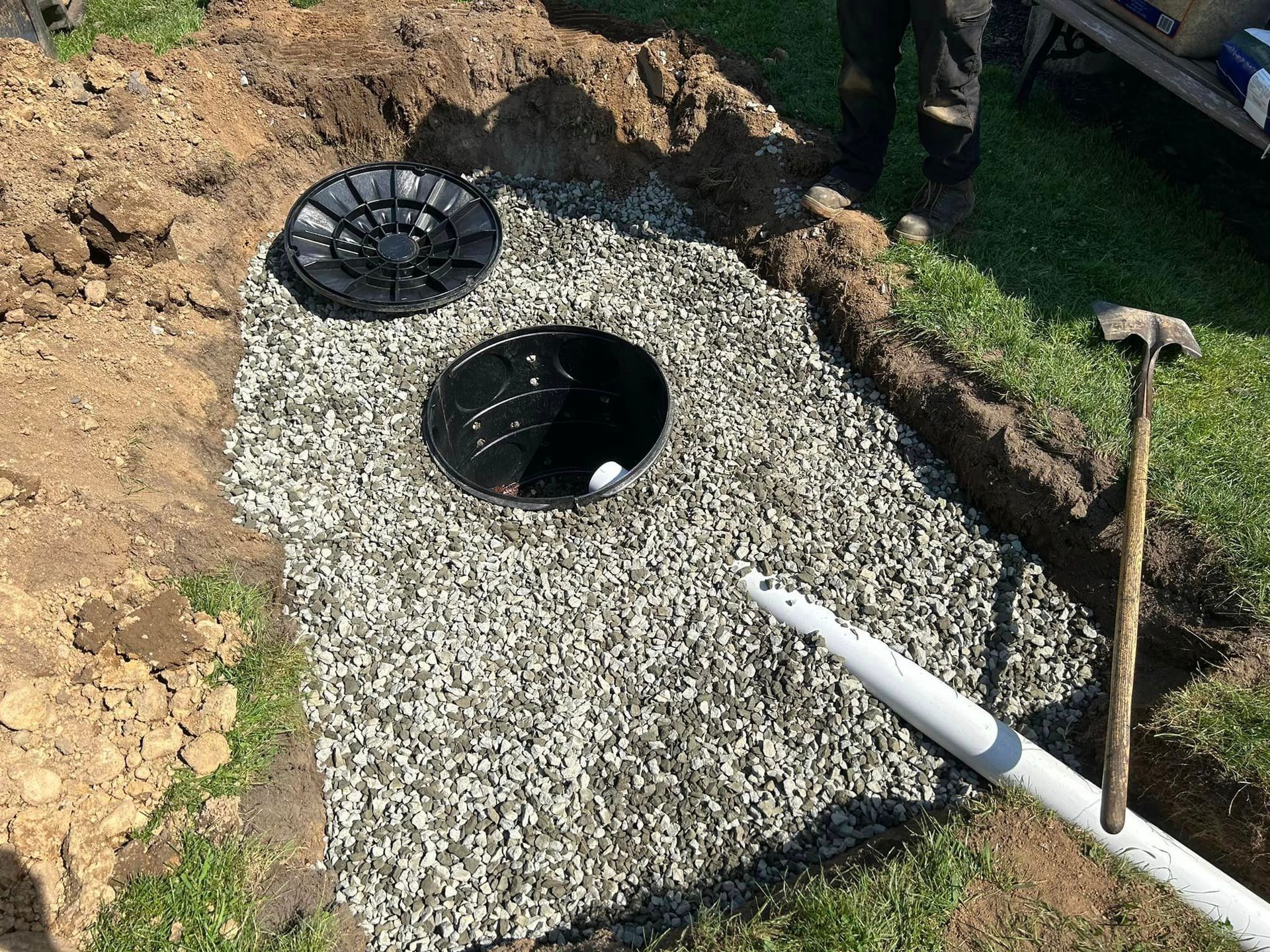 A man is digging a hole in the ground to install a septic tank.