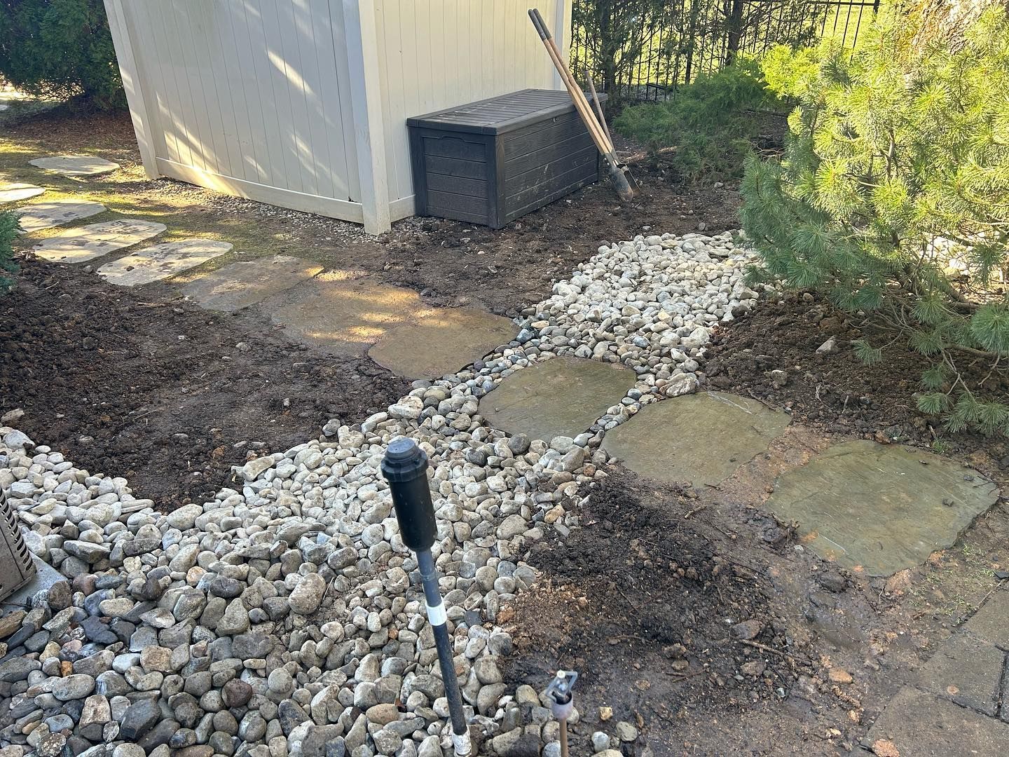 A shovel is sitting in the dirt next to a pile of rocks.