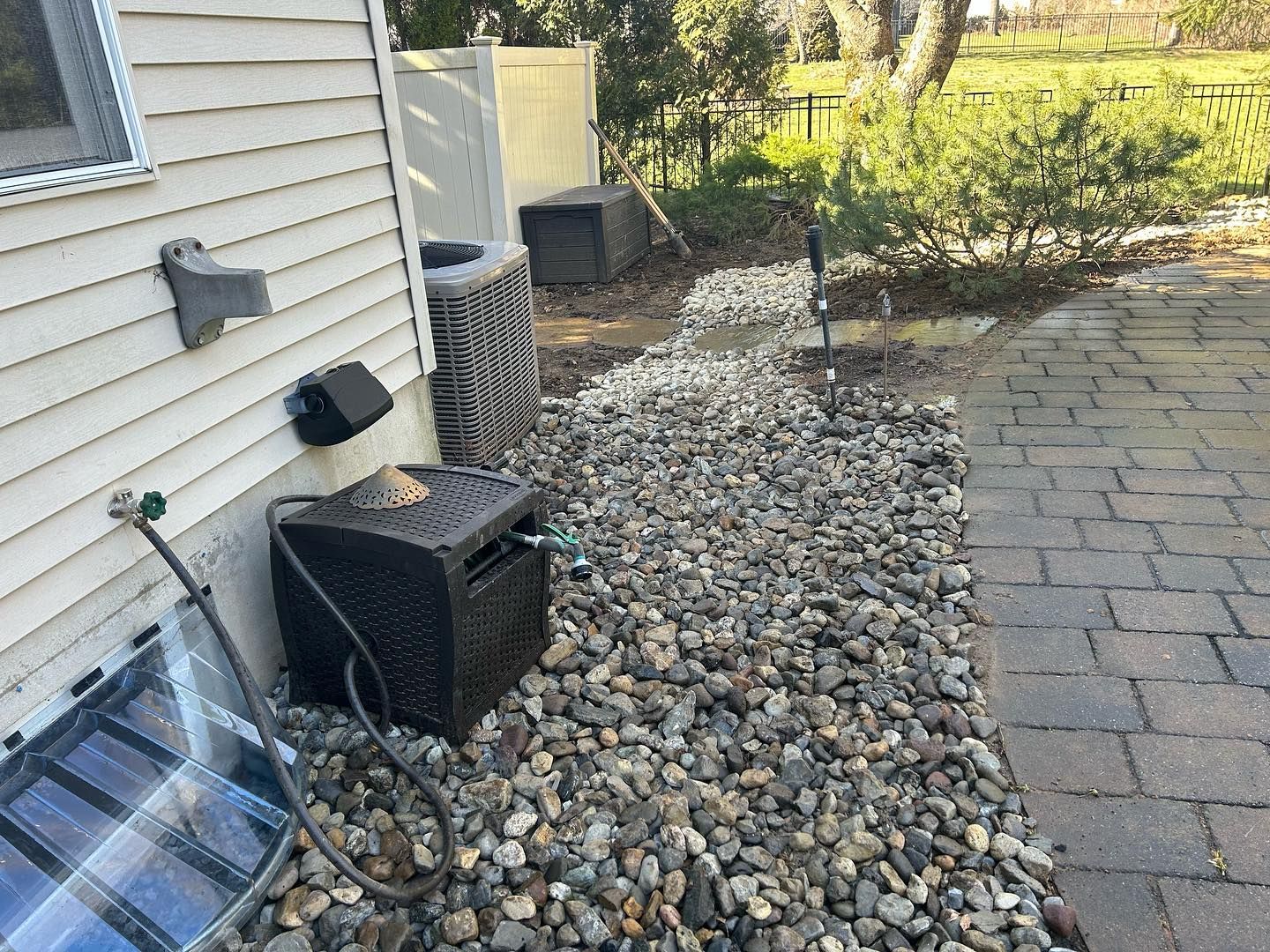 A black box is sitting on a pile of rocks next to a house.