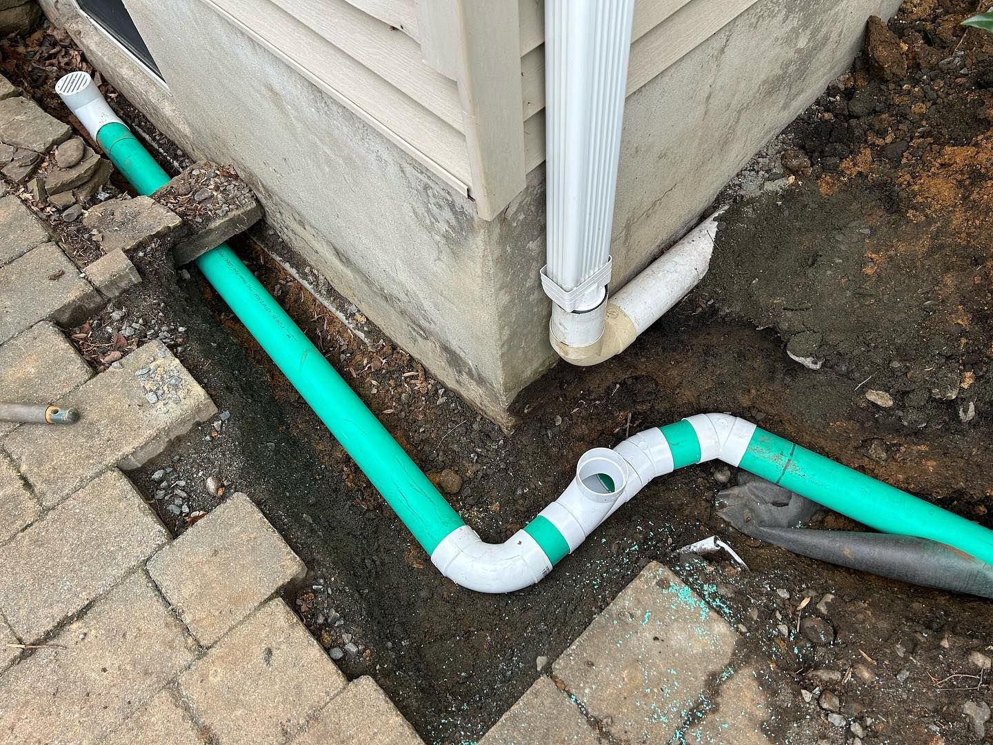 A drain pipe is being installed on the side of a house.