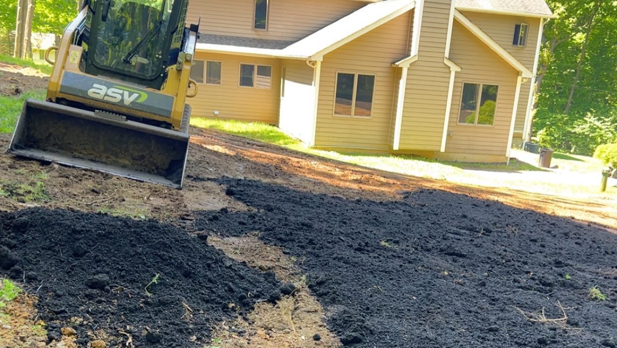 A bulldozer is moving dirt in front of a house.