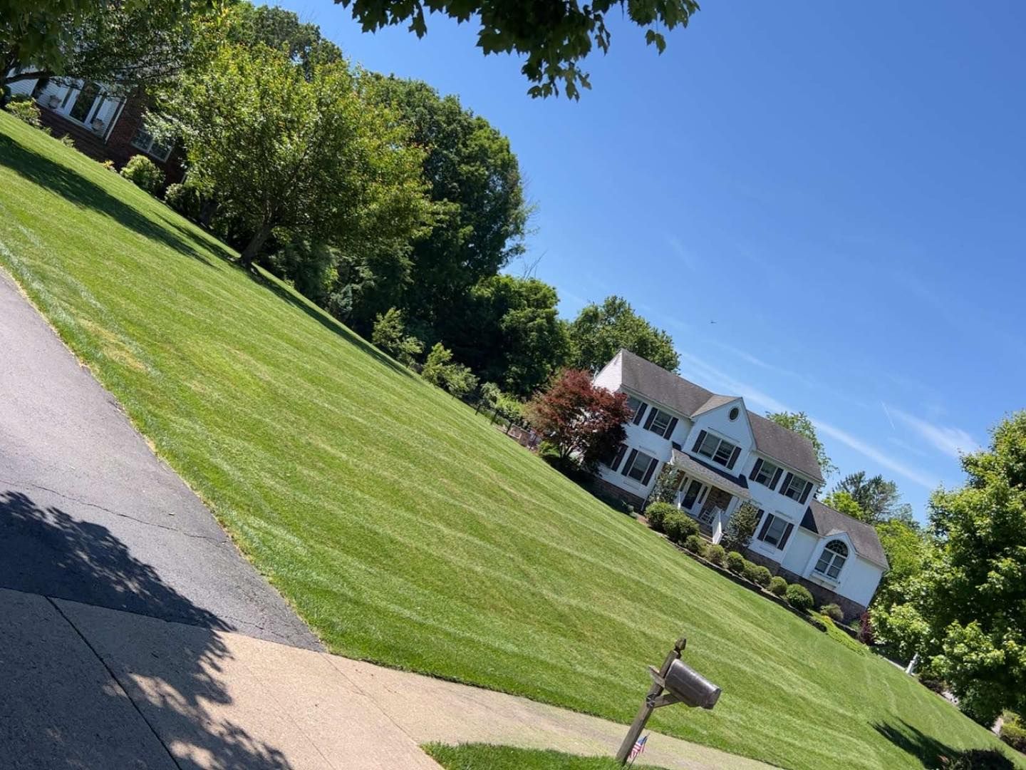 A large house is sitting on top of a lush green hill.