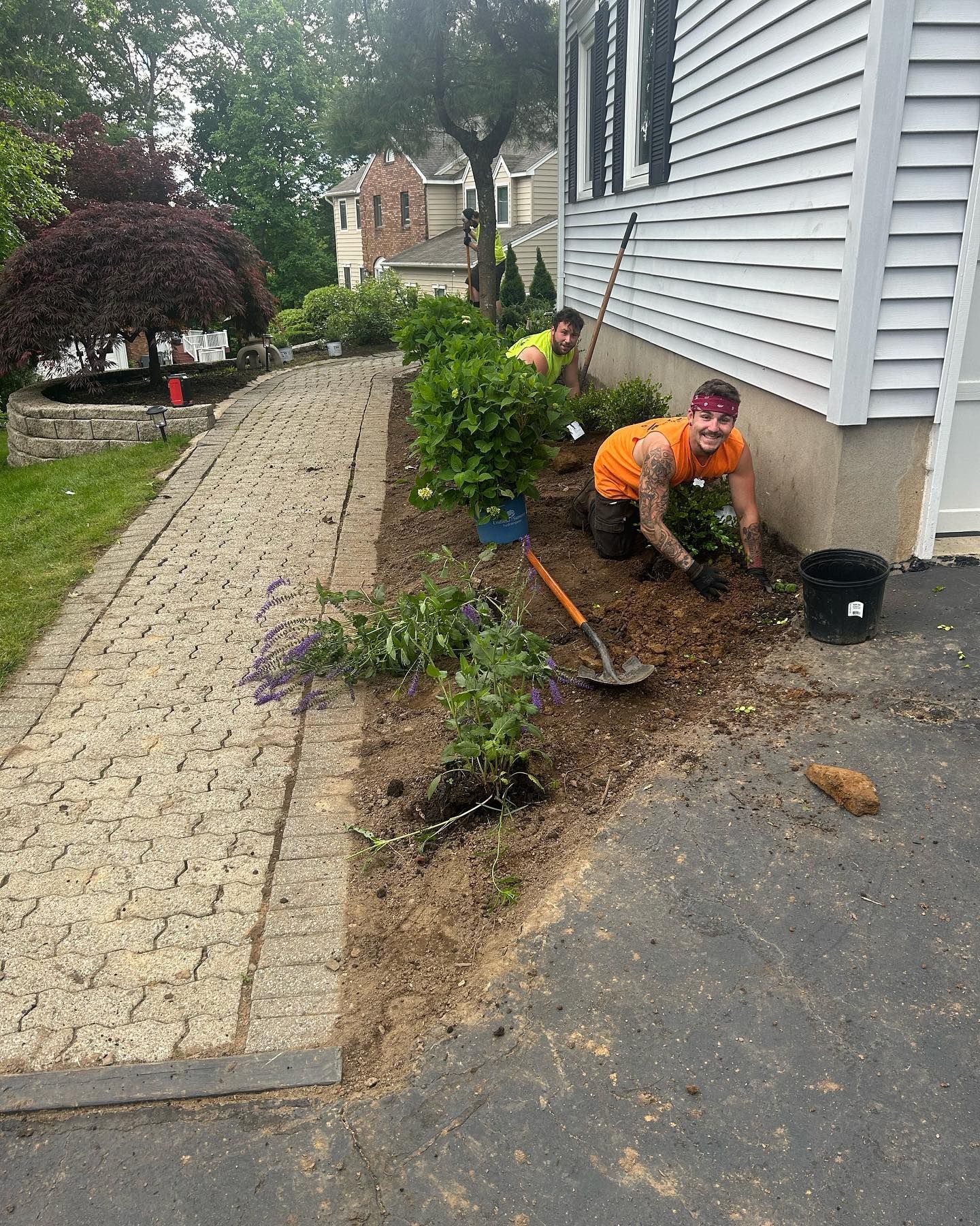 Two men are kneeling in the dirt in front of a house.
