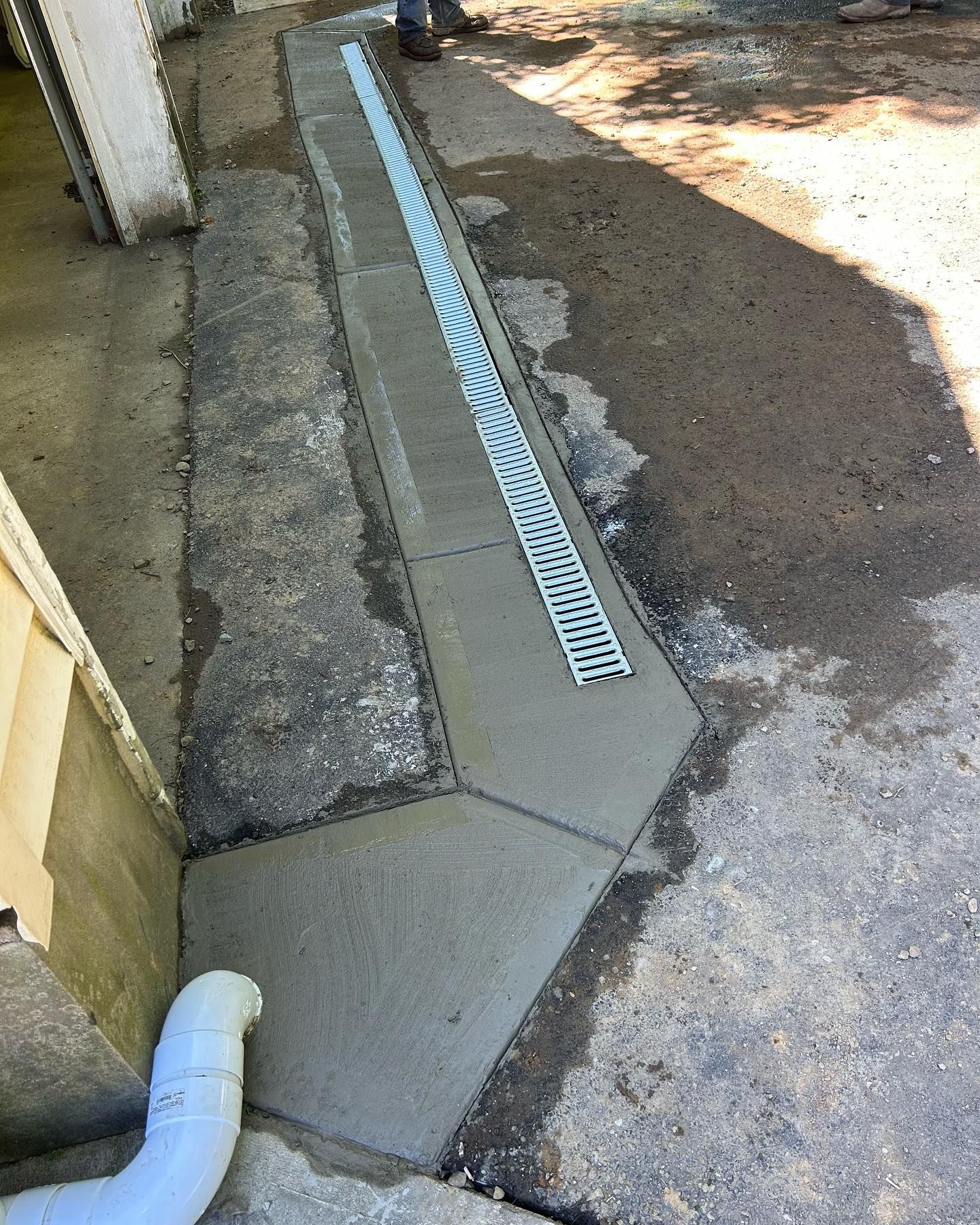 A man is standing next to a drain on a sidewalk.