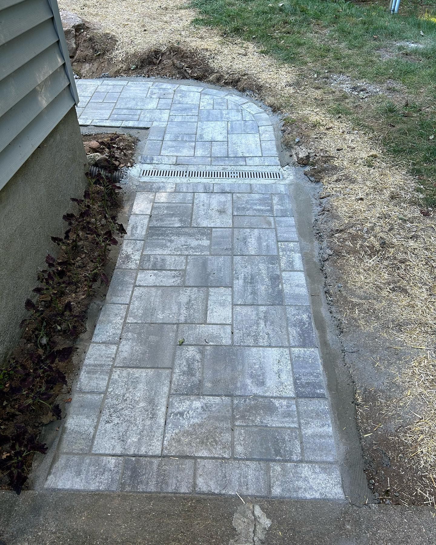 A brick walkway is being built next to a house.