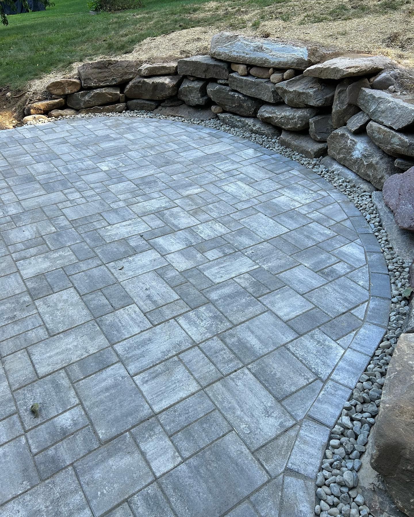 A brick patio with a stone wall in the background.