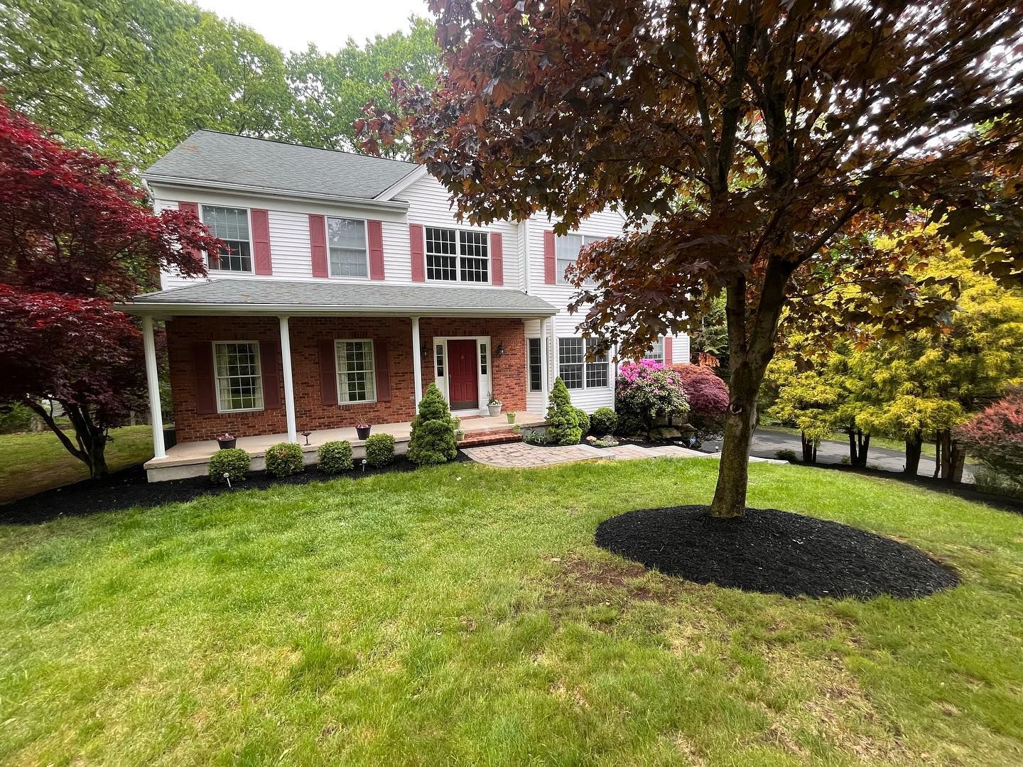 A large brick house with a large lawn and trees in front of it.