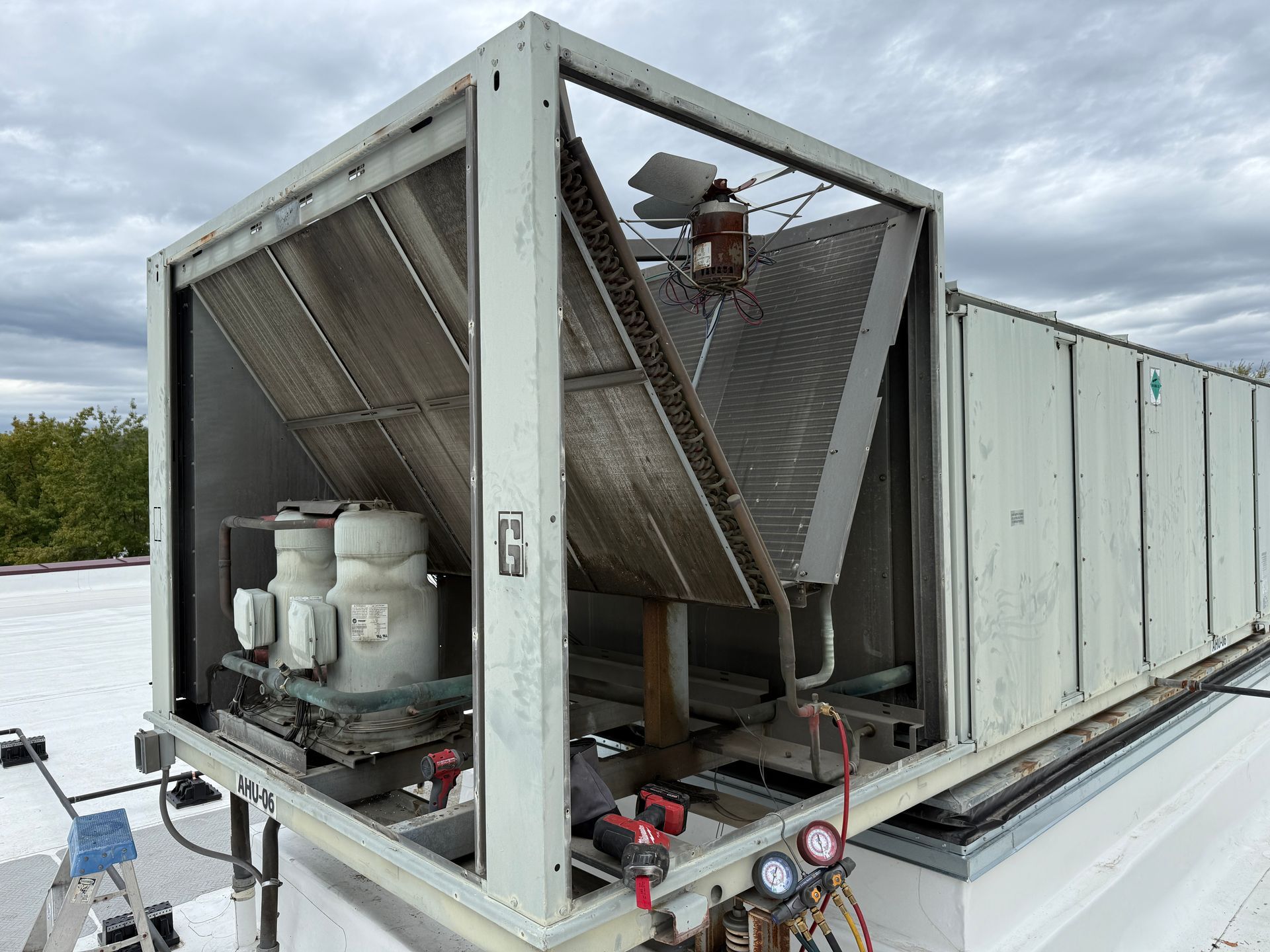 Large rooftop HVAC unit with angled metal fins, gauges, and electrical components.