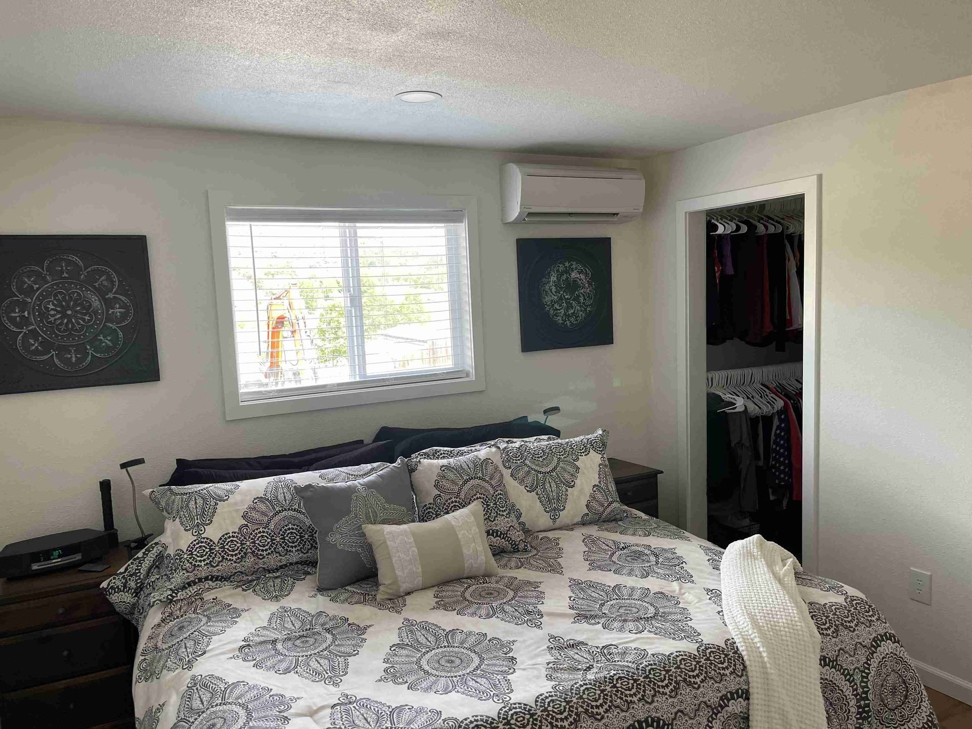 Bedroom with bed, closet, window, art, and air conditioning unit.