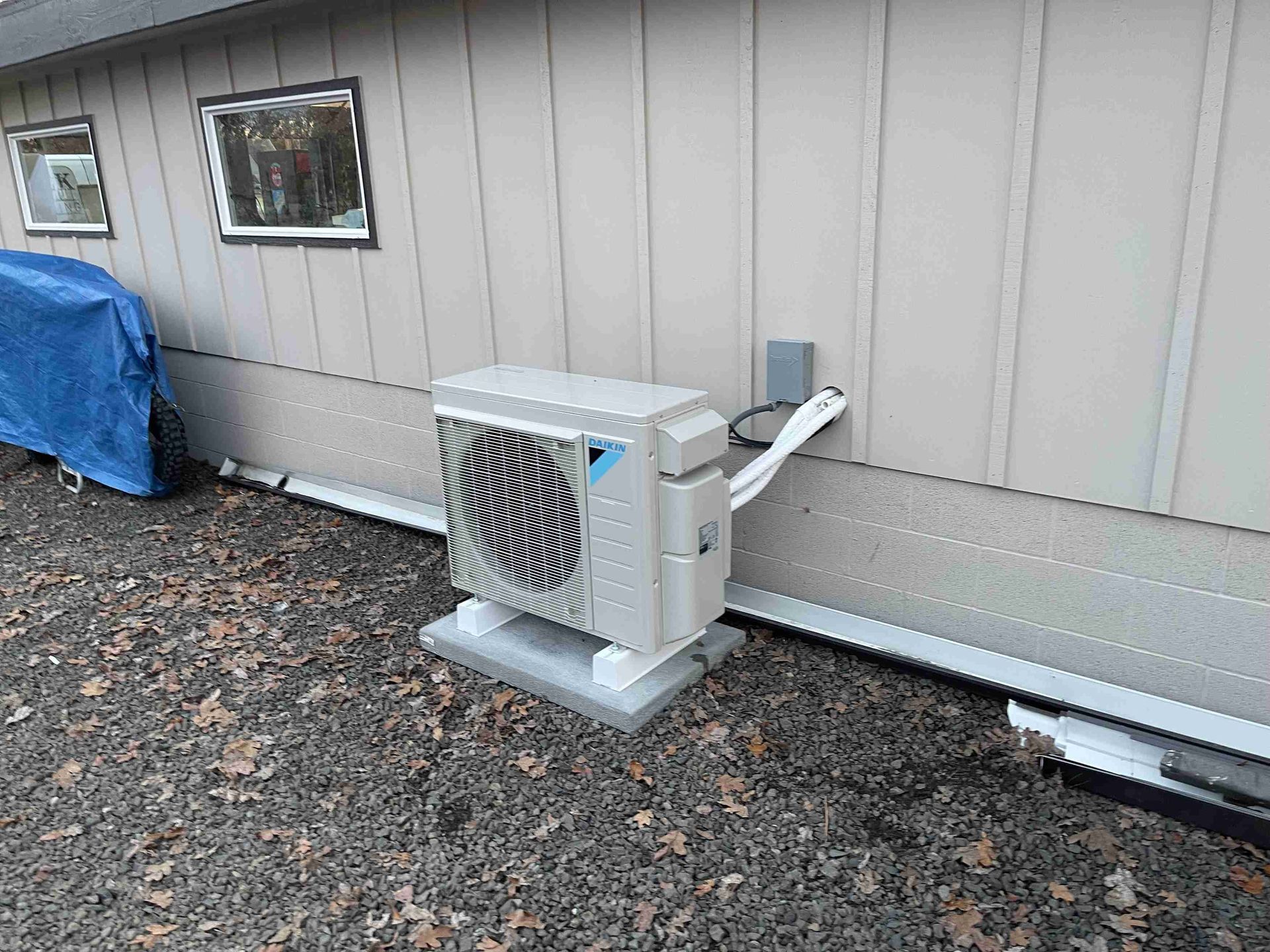 Outdoor air conditioning unit mounted on a concrete pad near a building's side.