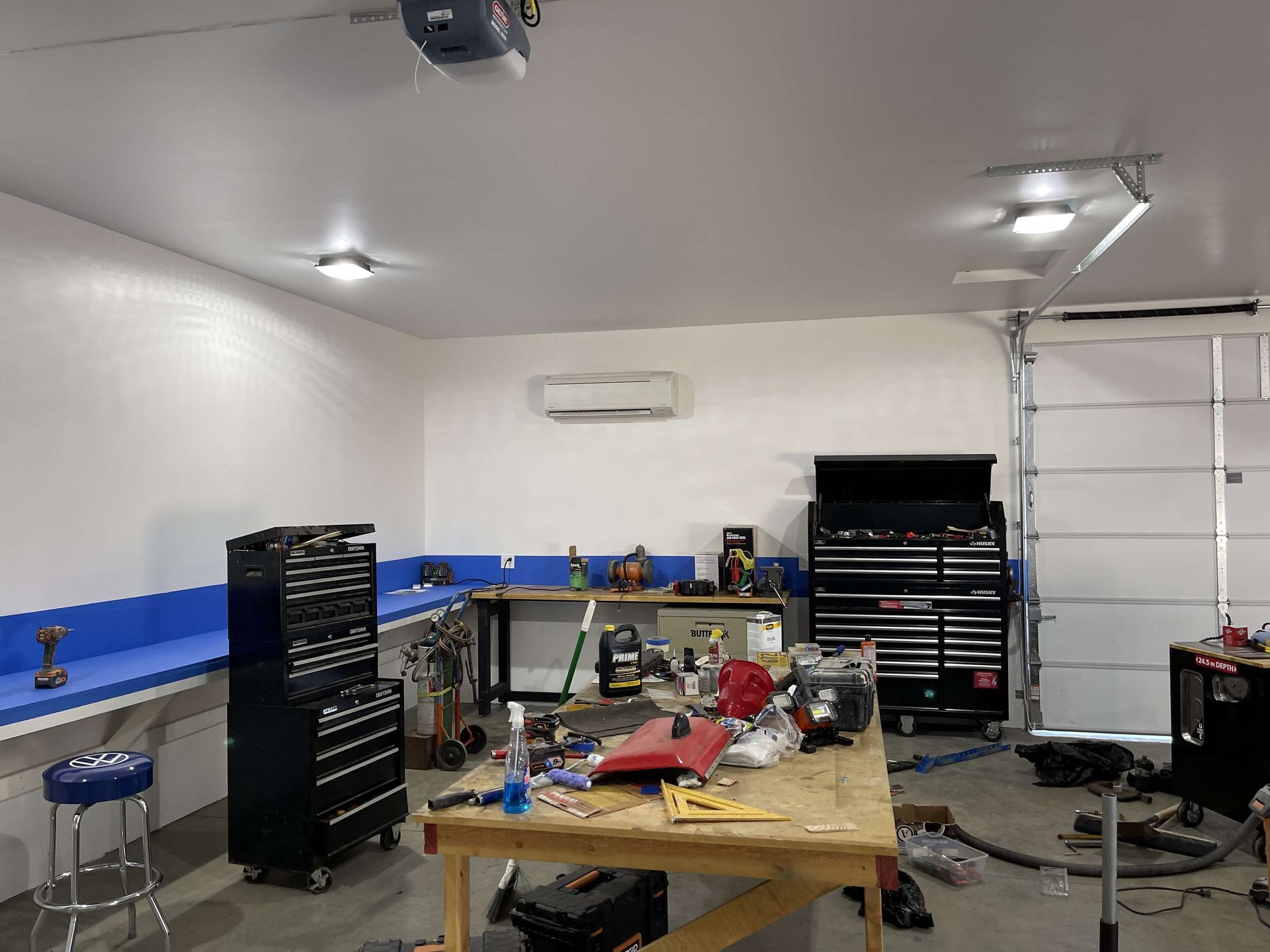Garage interior with workbenches, tools, and a garage door.
