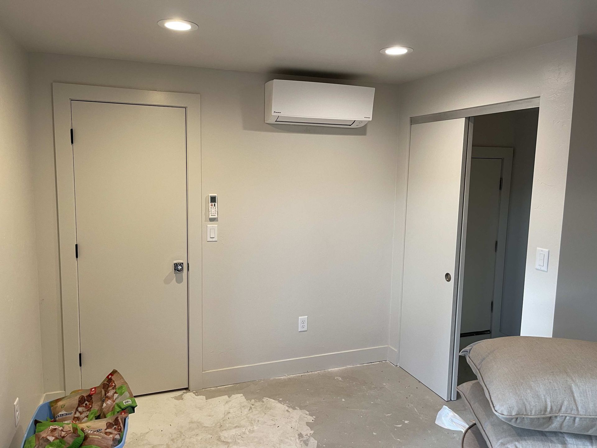 Interior room with two doors, AC unit, and debris on floor. Walls are painted light gray.