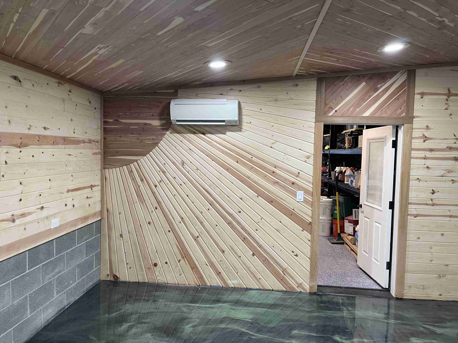 A room with wood-paneled walls and ceiling, including an air conditioner, doorway, and concrete block.