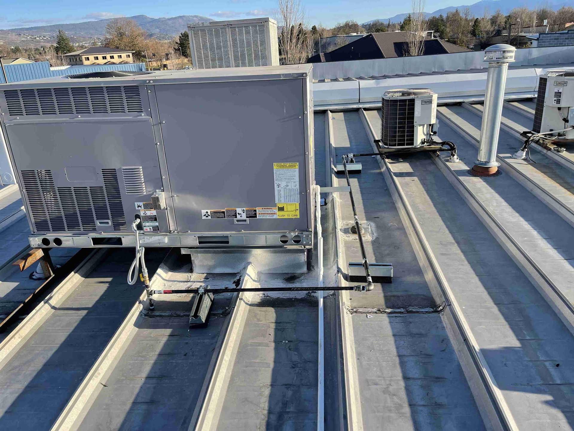 Rooftop with HVAC units on a corrugated metal roof. A large gray unit is centered.