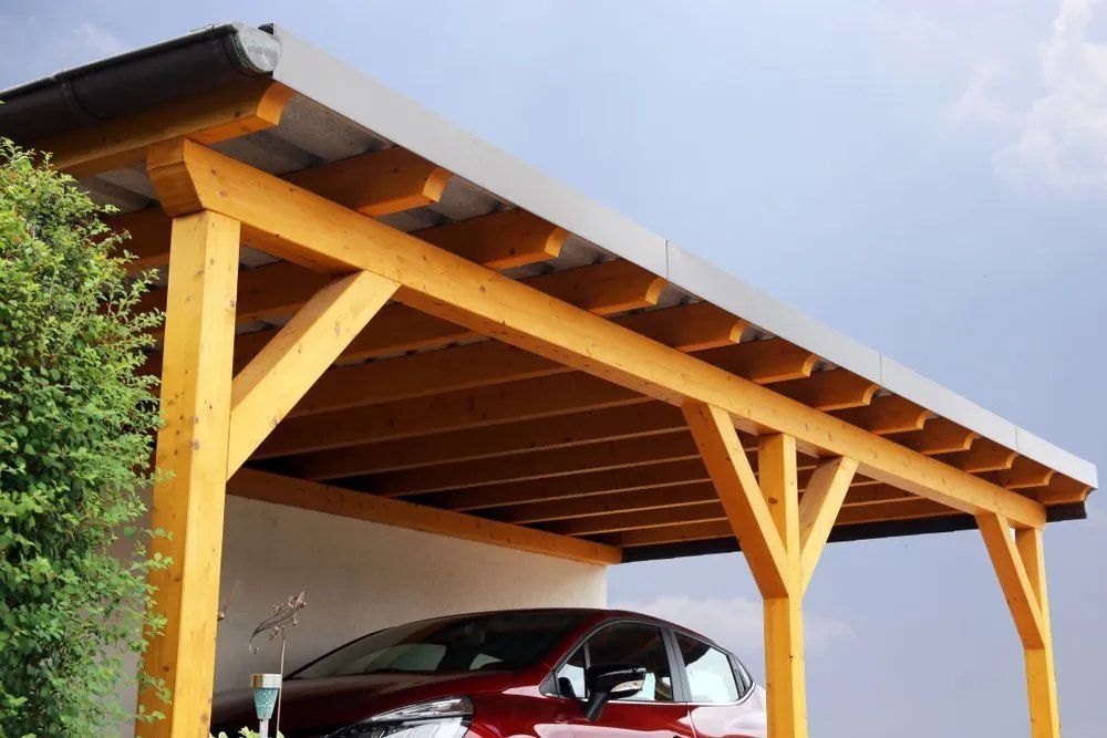 A Red Car Is Parked Under a Wooden Carport — Manning Valley Patios in Cundletown, NSW