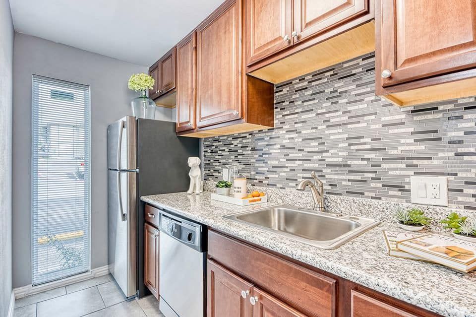 Kitchen with wooden cabinets, stainless steel appliances, granite countertops, and mosaic tile backsplash.