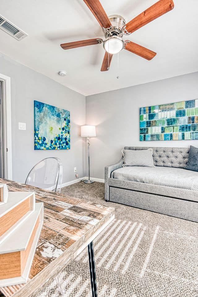 Bedroom with gray walls, a daybed, ceiling fan, artwork, and a patterned rug.