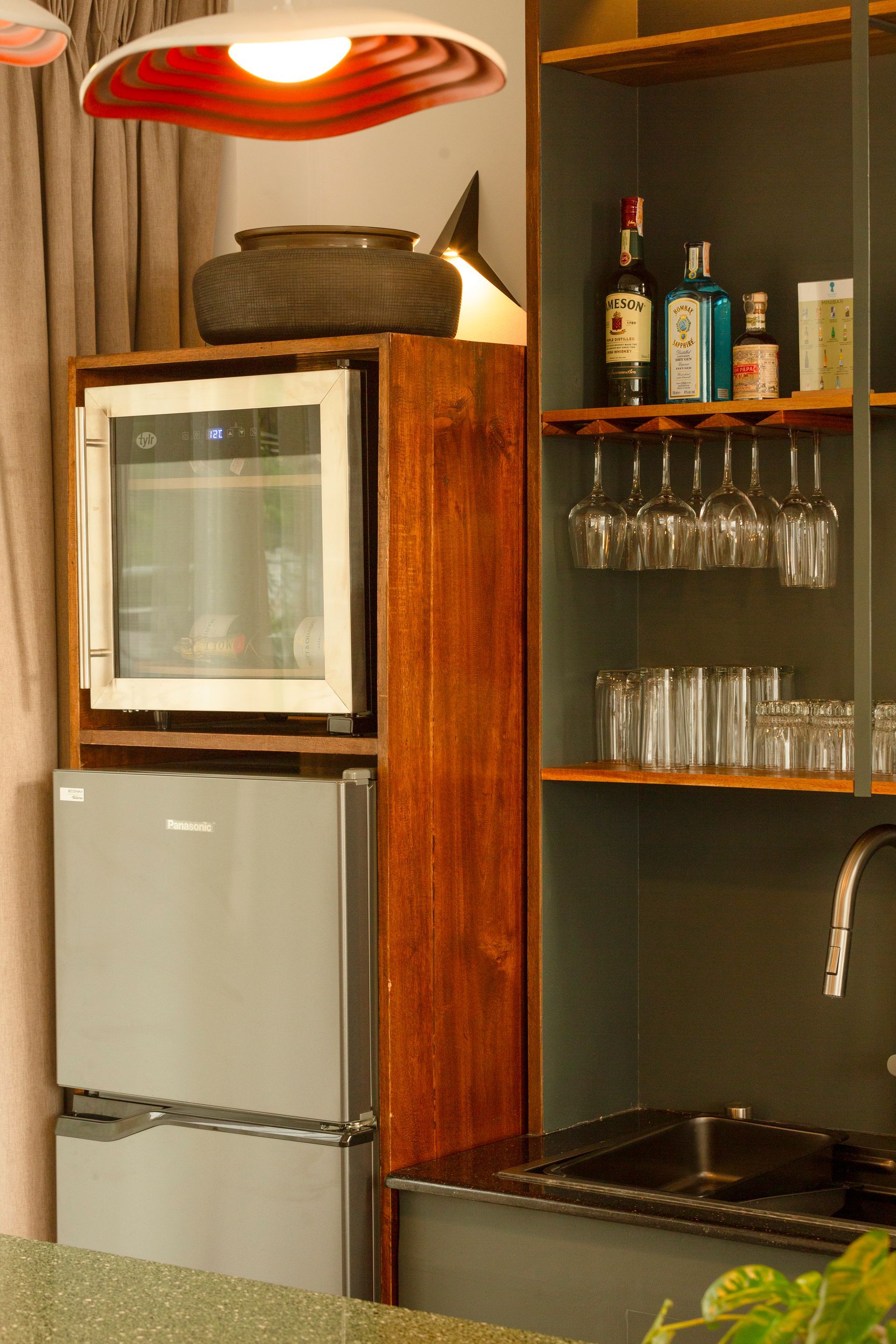 Built-in bar: mini-fridge, wine cooler, wooden shelves with liquor bottles, and glasses.