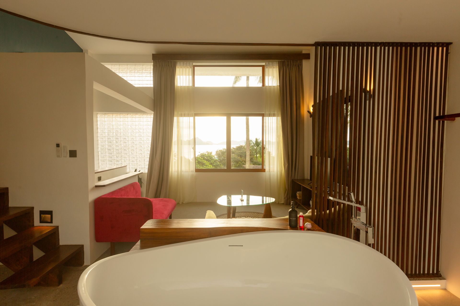 Bathroom interior with tub, window, and wooden screen. Soft light and neutral colors.