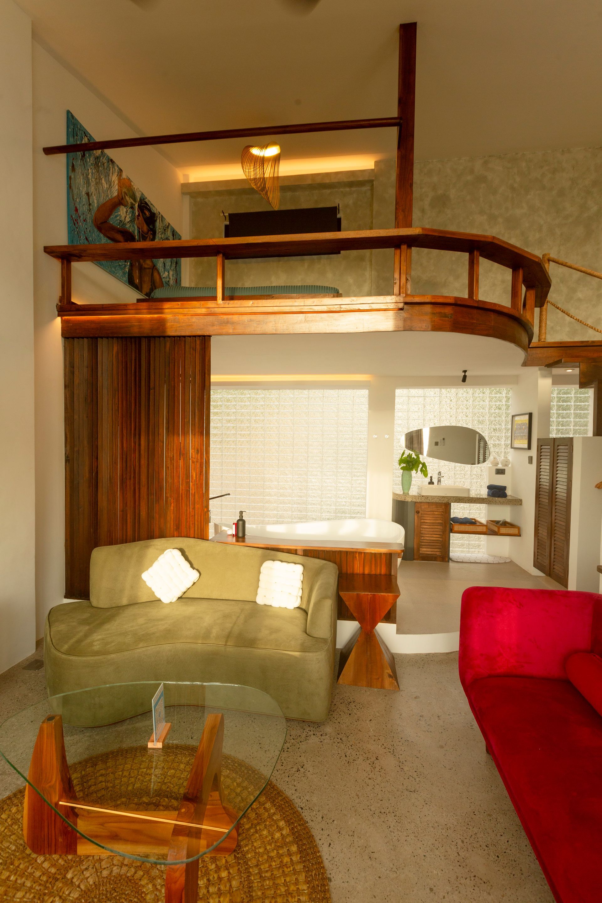 Living room with a loft, olive green couch, red couch, and wood accents.