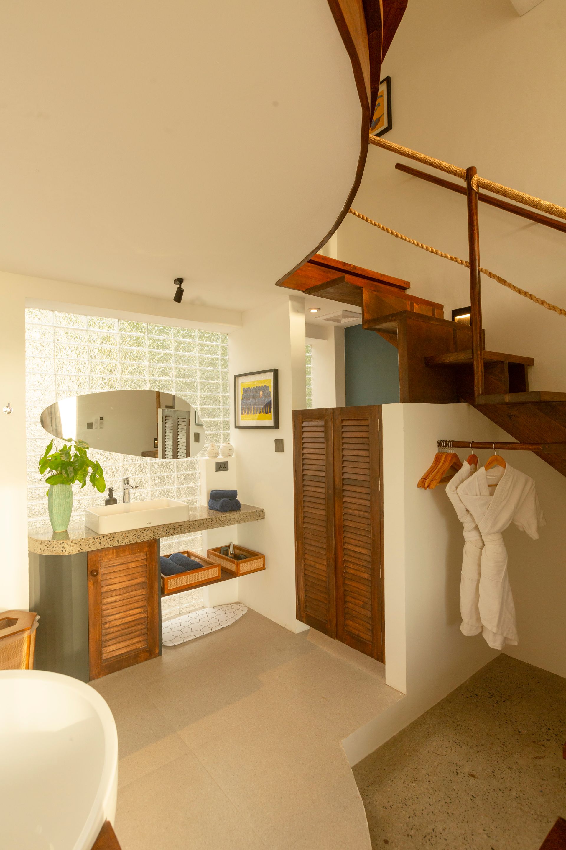 Bathroom with wooden spiral staircase and vanity area.  Robe hanging on wall.
