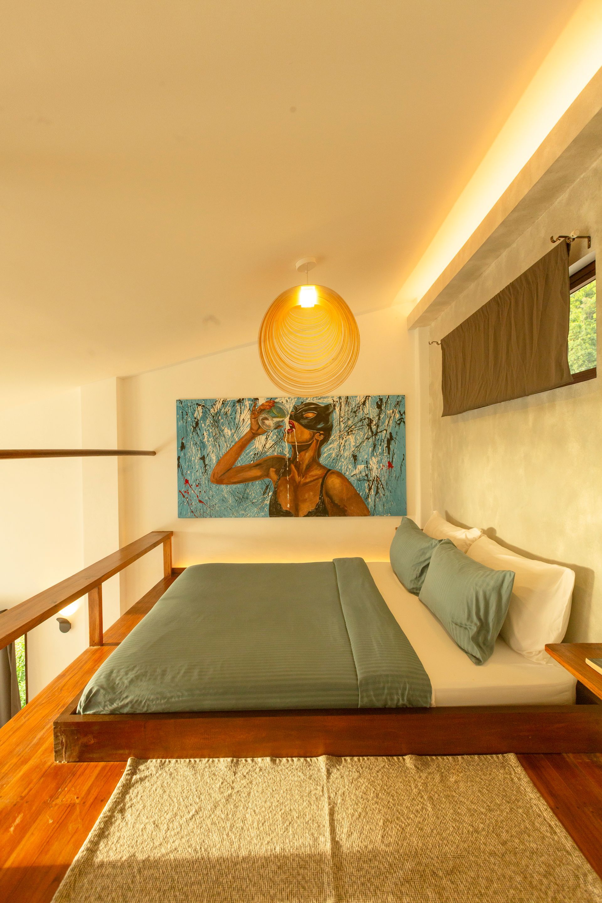 Bedroom loft with bed, large artwork, and woven pendant light.