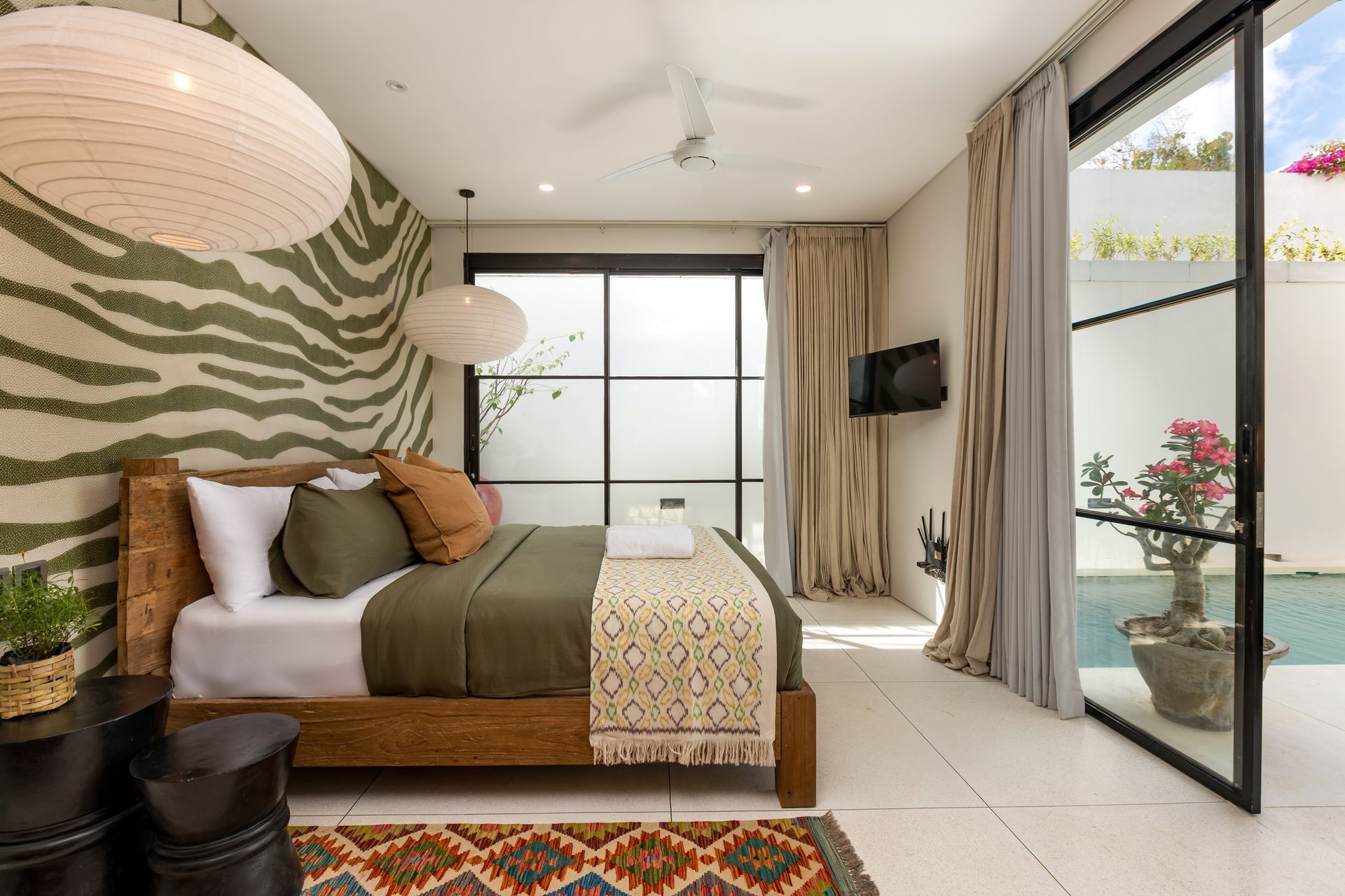 Bedroom with wooden bed, zebra-print wallpaper, and sliding door to pool area.
