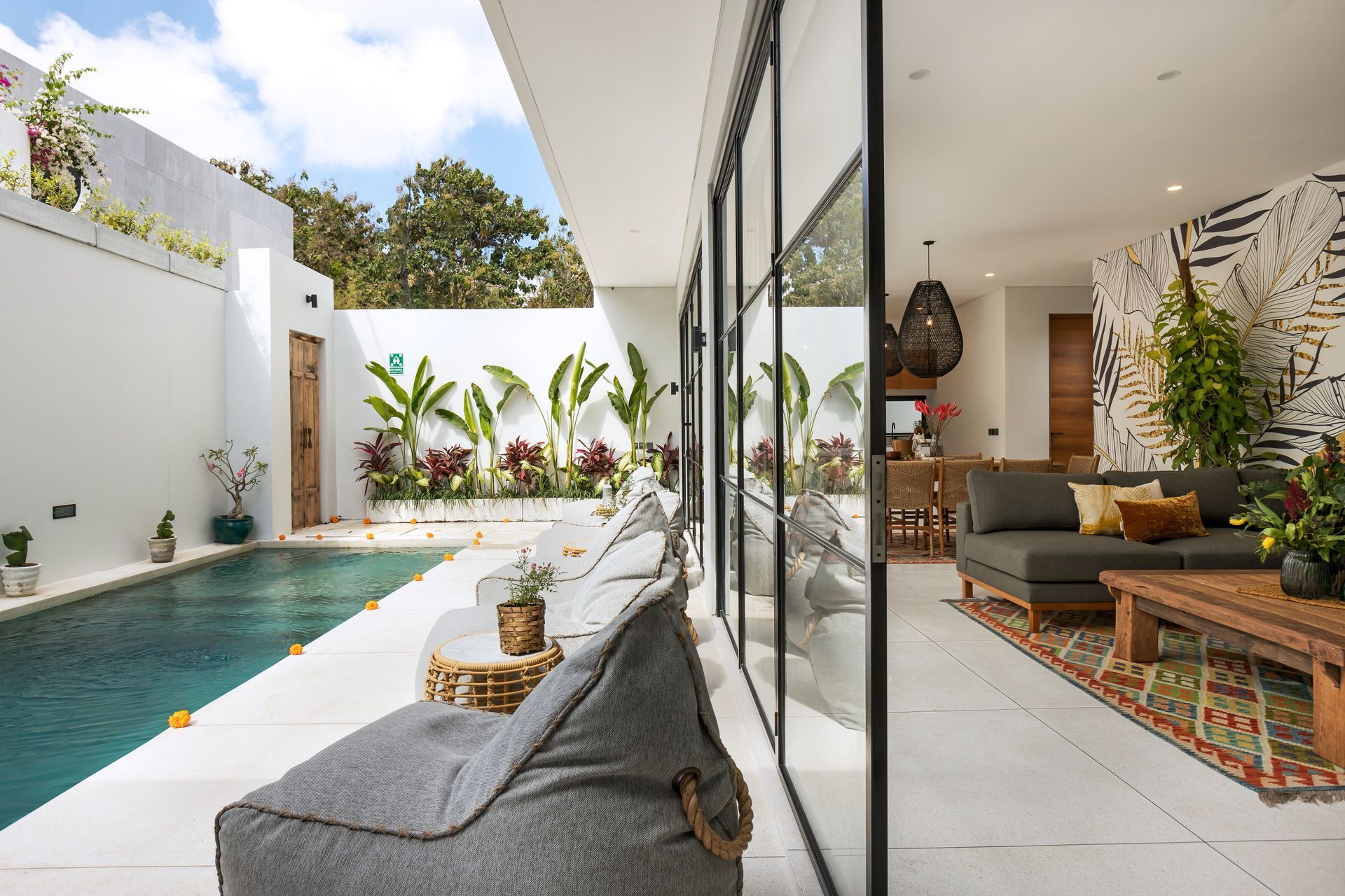 Poolside villa with beanbag chairs, pool, and open-plan living area with glass doors.