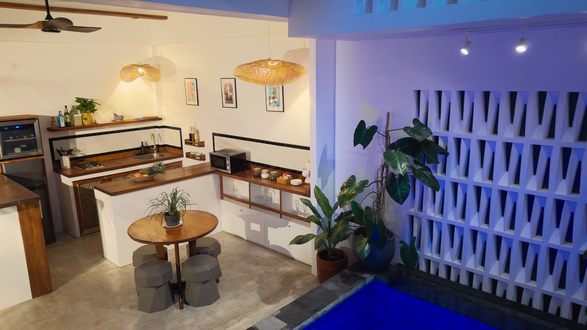 Interior shot of a modern kitchen with a round dining table, a pool, and decorative wall.