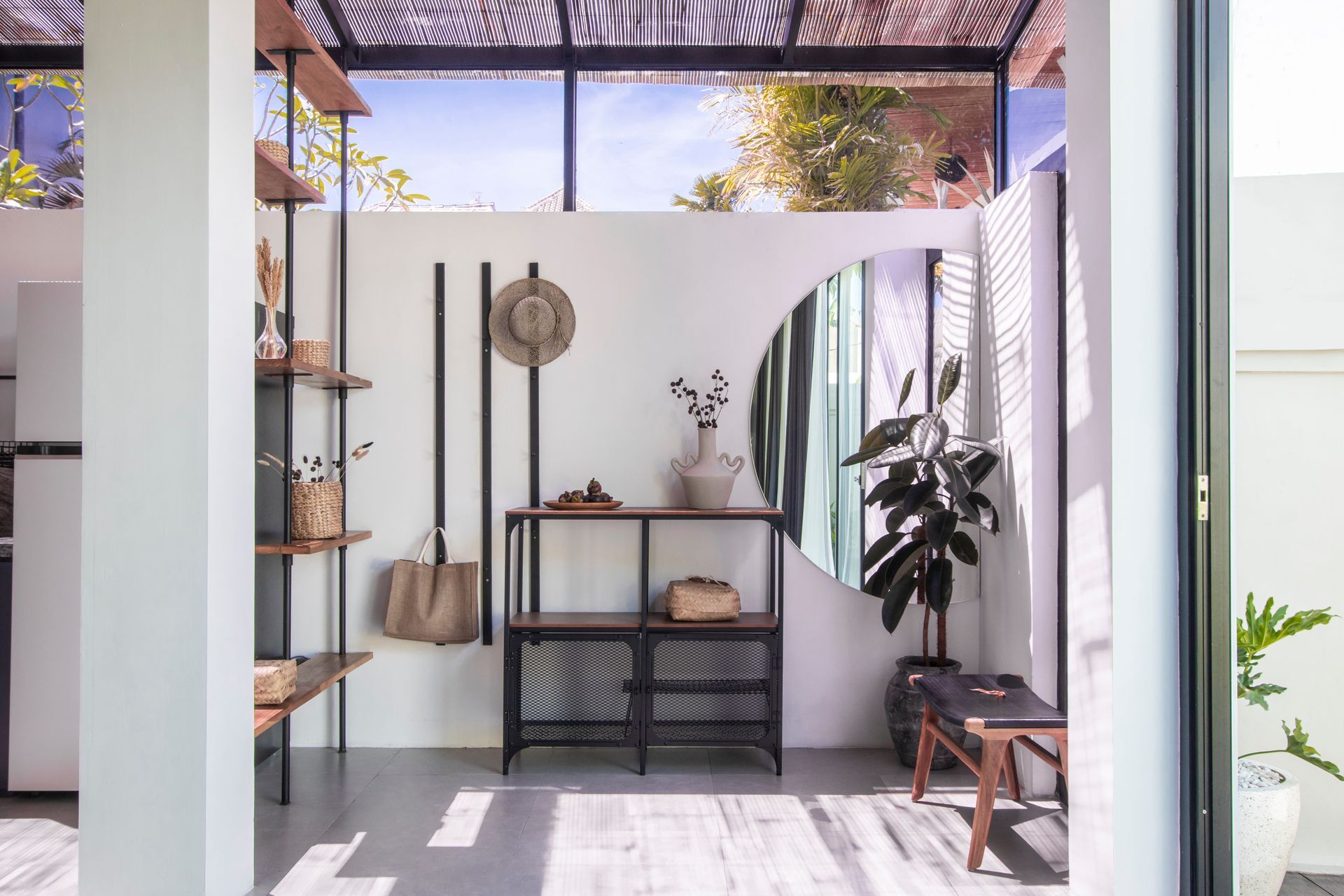 Interior space with shelves, decorative items, a mirror, and a bench. The area is bright, with light and shadows.