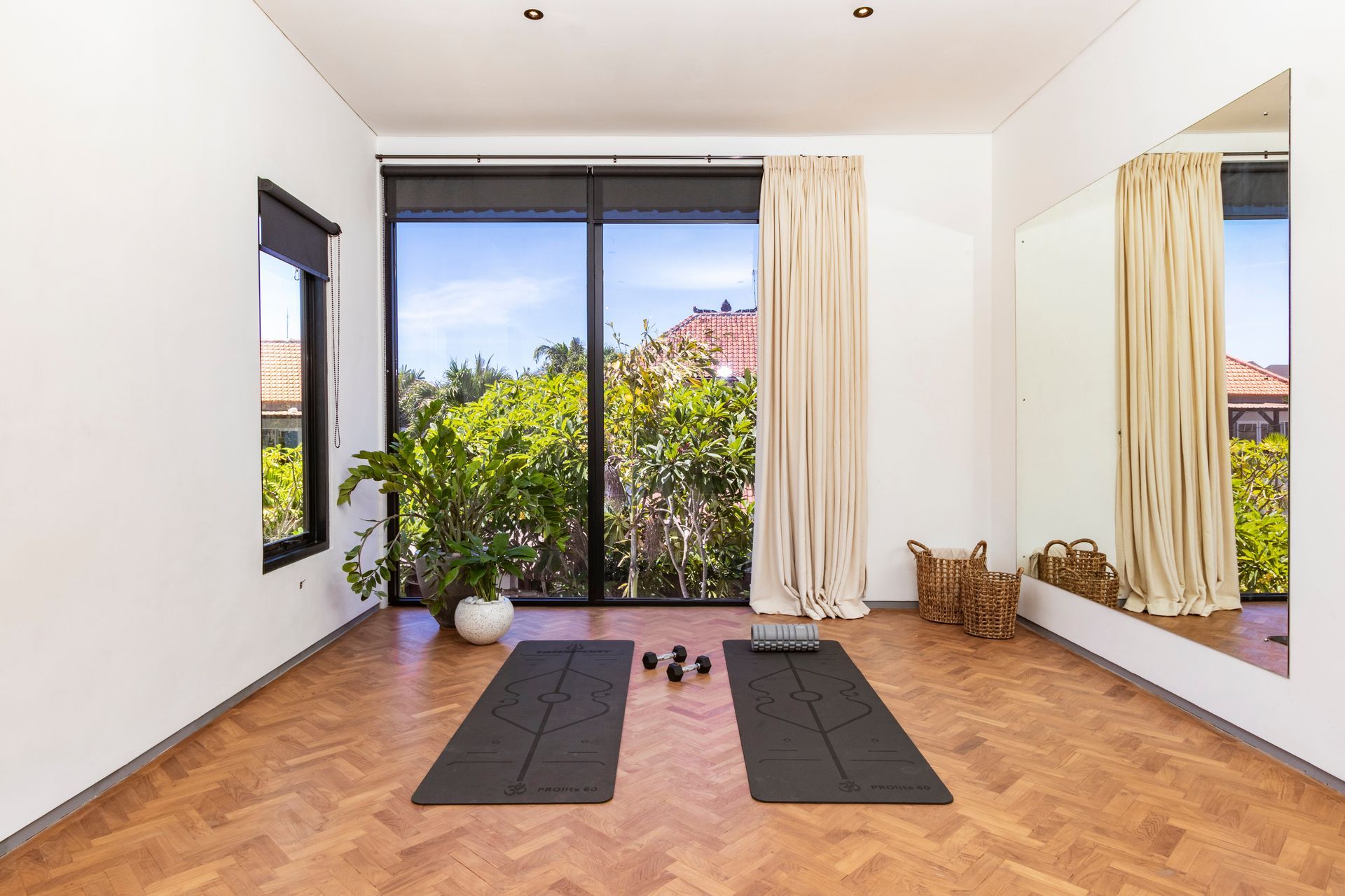 Yoga studio with mats, weights, and large window overlooking trees.