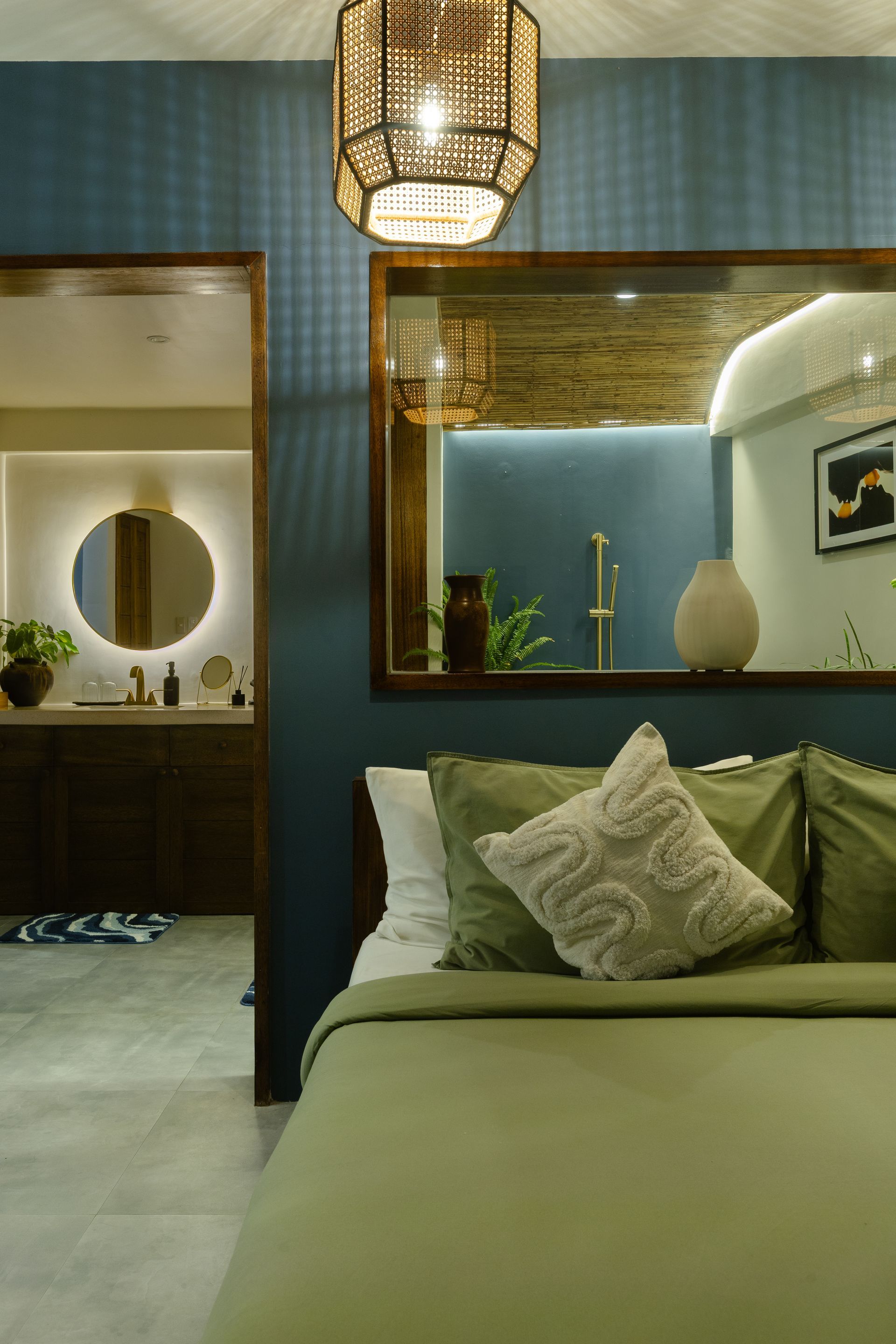 Bedroom with olive green bedding, navy blue wall, a woven light fixture, and a mirrored wall.