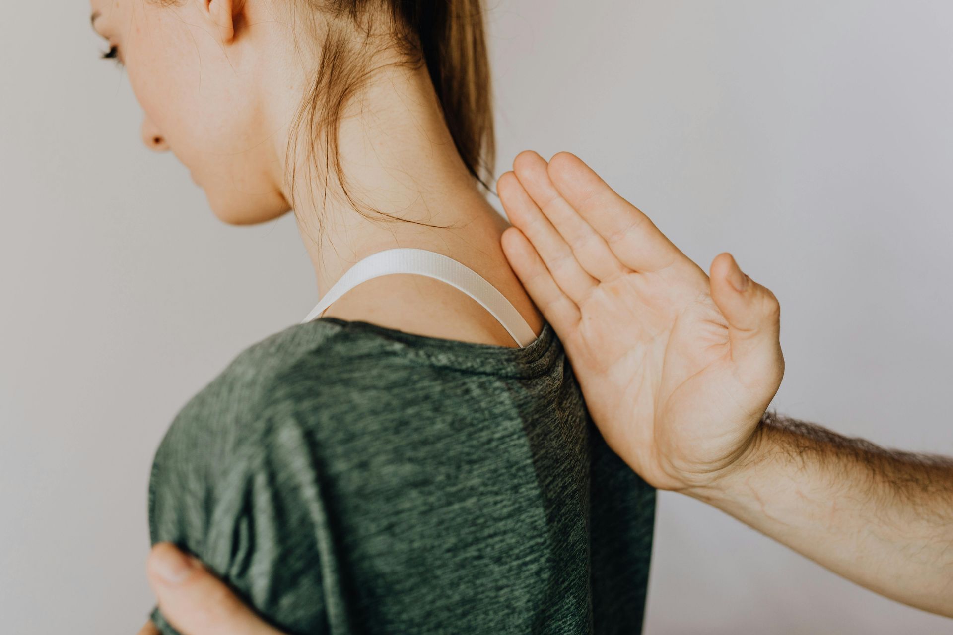 Person receiving a massage on the neck and shoulder, white bra strap visible.